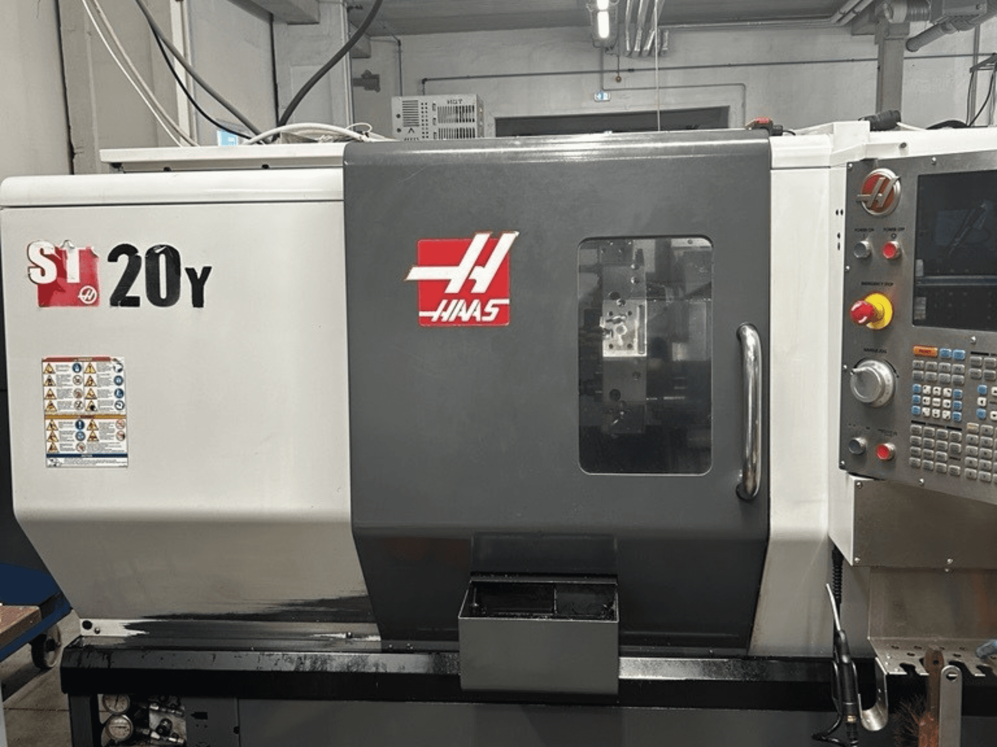 Токарний верстат з ЧПК Haas ST-20Y, вид спереду, з панеллю керування, етикетками безпеки та робочим вікном.