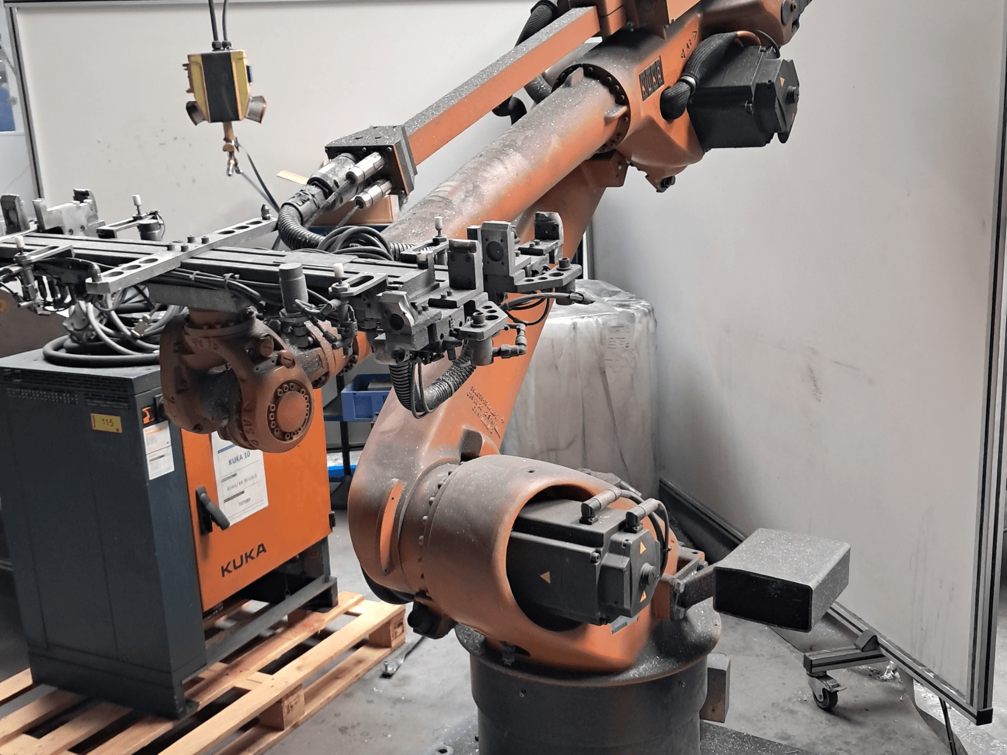 Роботизована рука KUKA KR 30L16-2 у боковому ракурсі, з складним кінцевим ефектором та кабелями управління, розташована поруч із блоком управління KUKA.