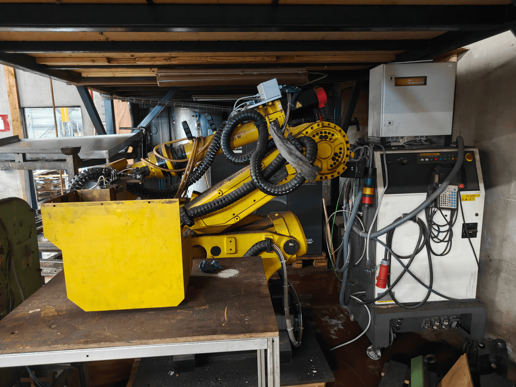 Вигляд спереду маніпулятора робота FANUC S-430i W жовтого кольору з панеллю керування, кабелями та жовтим компонентом на робочому столі.