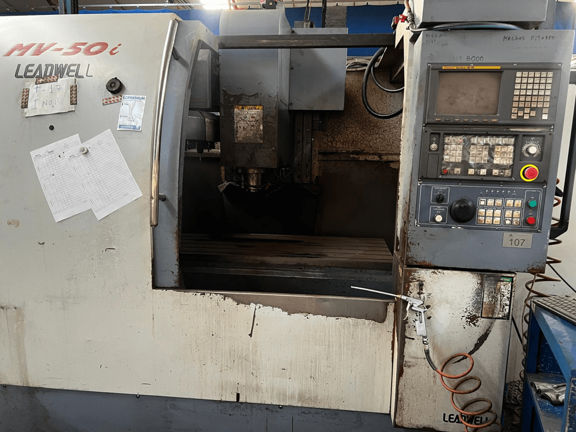 Вертикальний обробний центр Leadwell MV-50i, вид спереду, на якому видно панель управління, зону шпинделя та робочий стіл із слідами зносу.