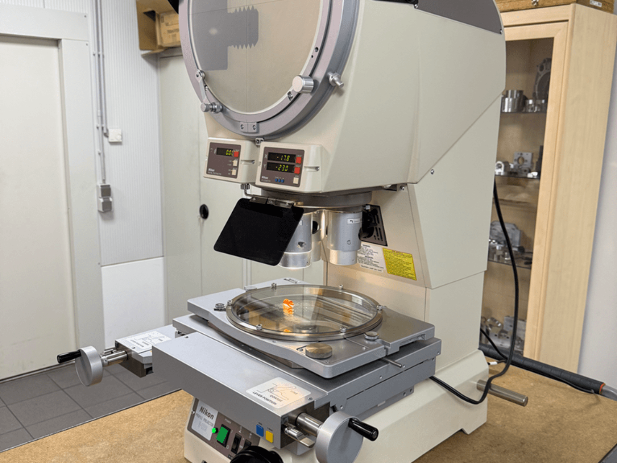 Модель мікроскопа Nikon спереду, з цифровими дисплеями, регульованим столиком і круглою скляною пластиною.