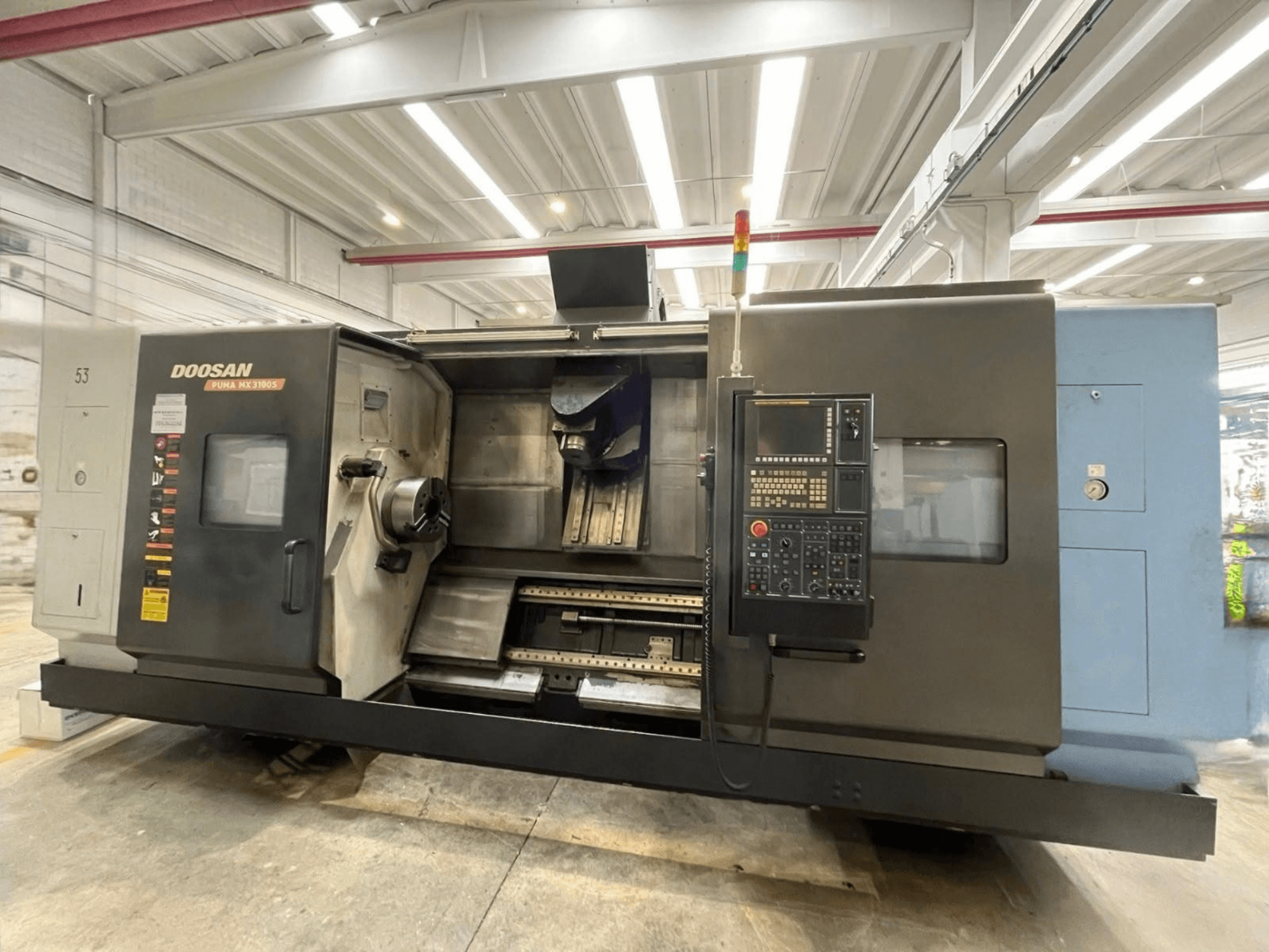 Вигляд спереду горизонтального токарного верстата DOOSAN PUMA MX3100 з панеллю керування та видимими шпинделем і зоною кріплення інструменту.