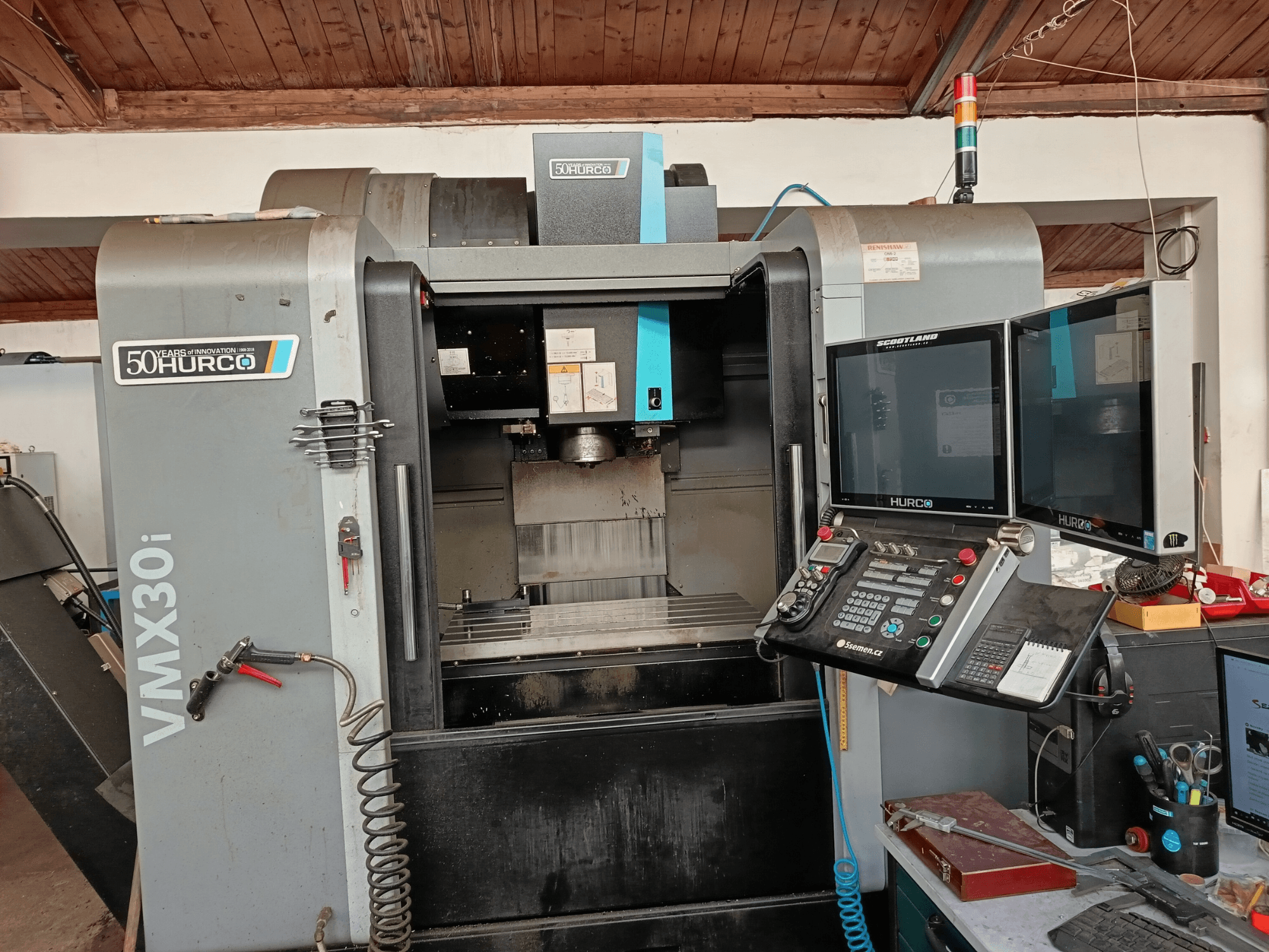 Фрезерний верстат з ЧПК Hurco VMX30i спереду, з двома моніторами, панеллю керування та приєднаним шлангом.