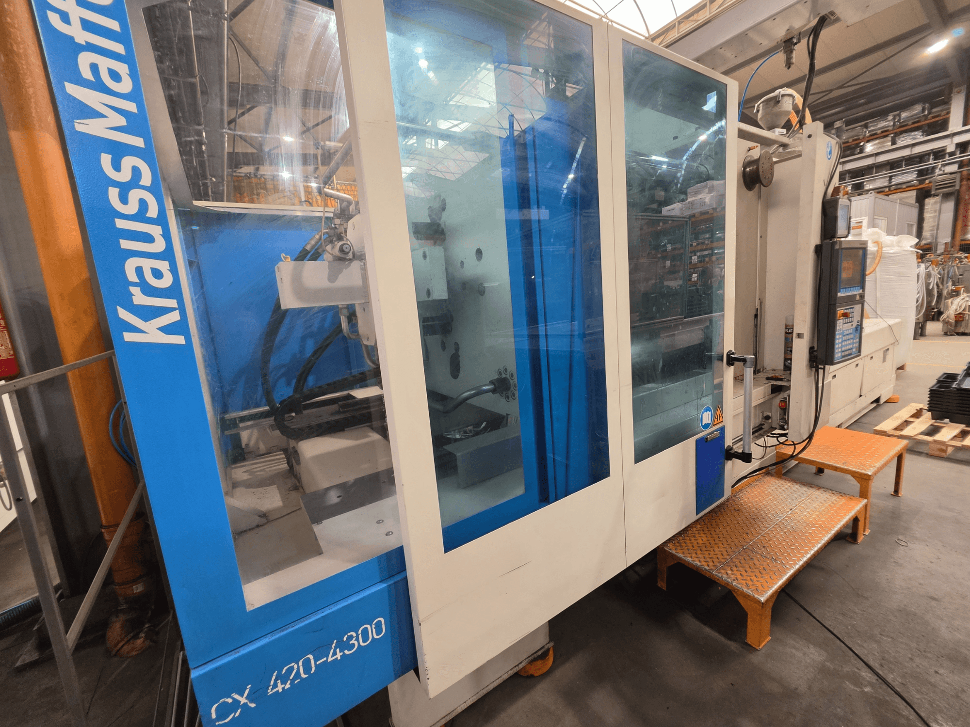 Гідравлічний термопластавтомат Krauss Maffei CX 420-4300, вид збоку, показана панель керування та прозорі панелі.