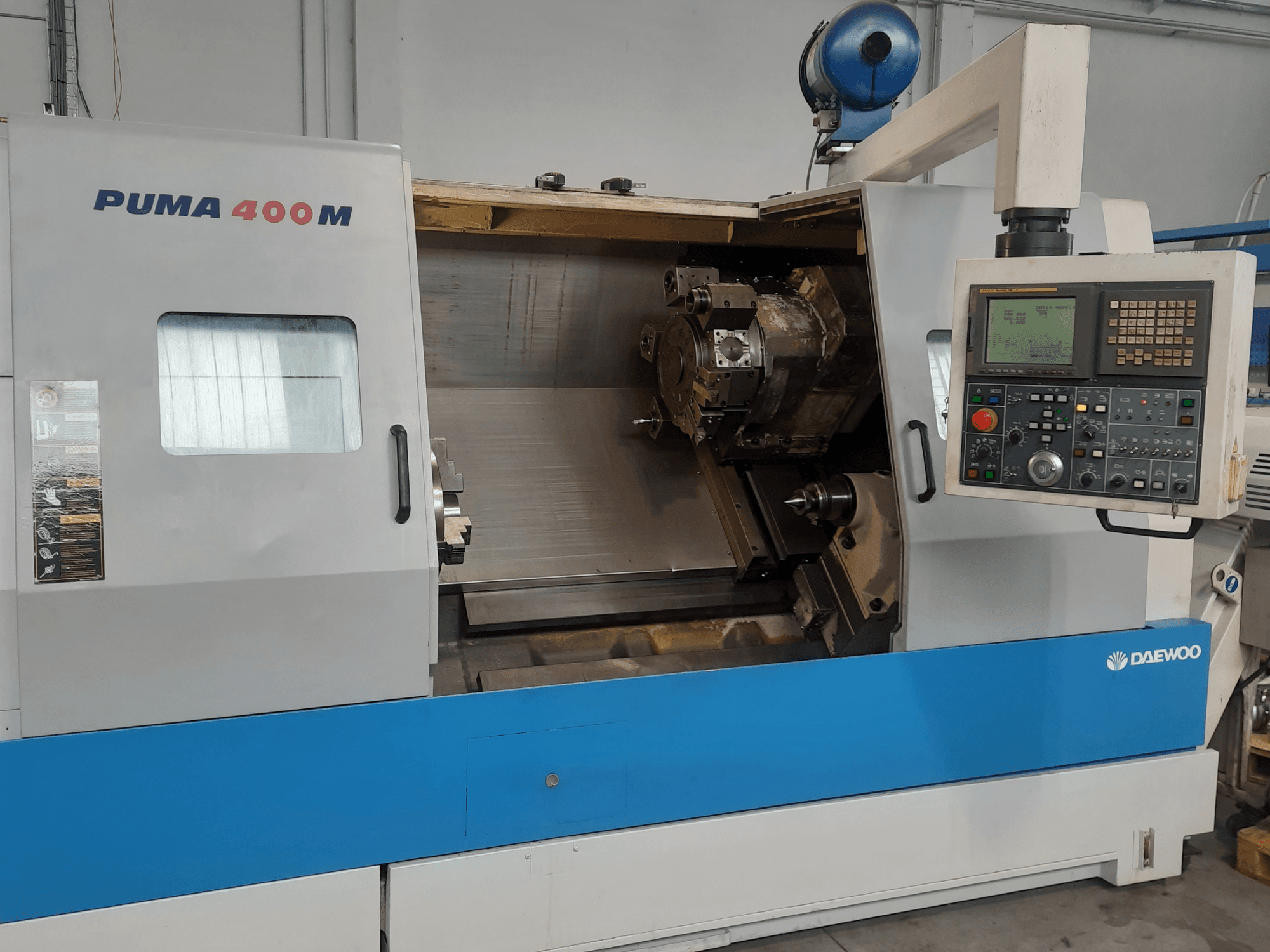 Вигляд спереду горизонтального токарного верстата DAEWOO PUMA 400MB, на якому видно органи управління та різальний інструмент у робочій камері.