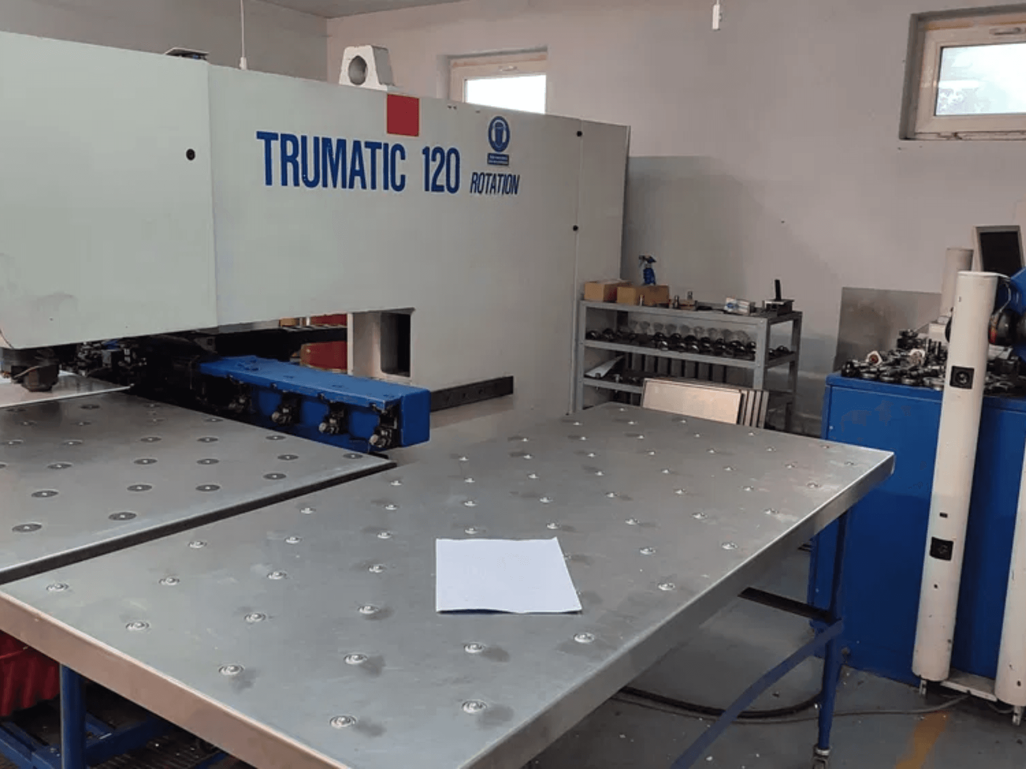 Перфоратор TRUMPF TRUMATIC 120R з ЧПУ, вид спереду, з металевим столом з пробитими отворами і чистим аркушем.