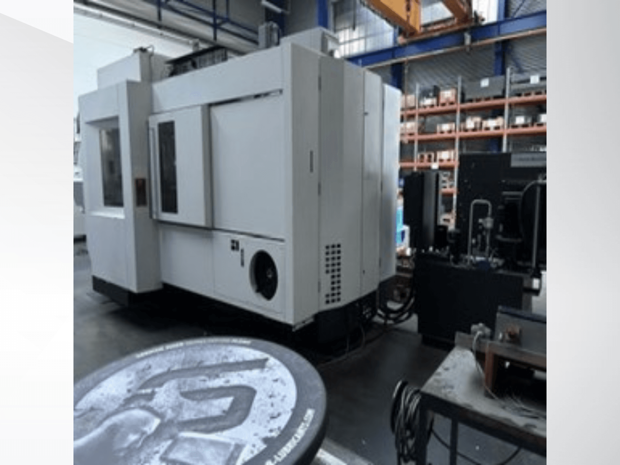 Білий універсальний обробний центр MIKRON HPM 1350 U у цеху; вид збоку, на якому видно велику панель управління та промислове оточення.