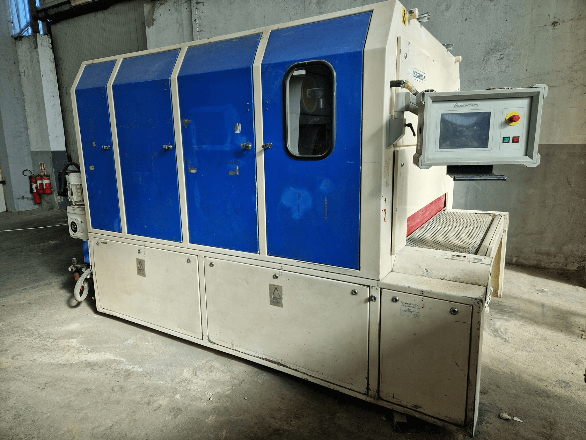 Промислова машина від бренду "Sedecom", вид збоку; має сині панелі, екран управління та текстуровану поверхню для переміщення продуктів.