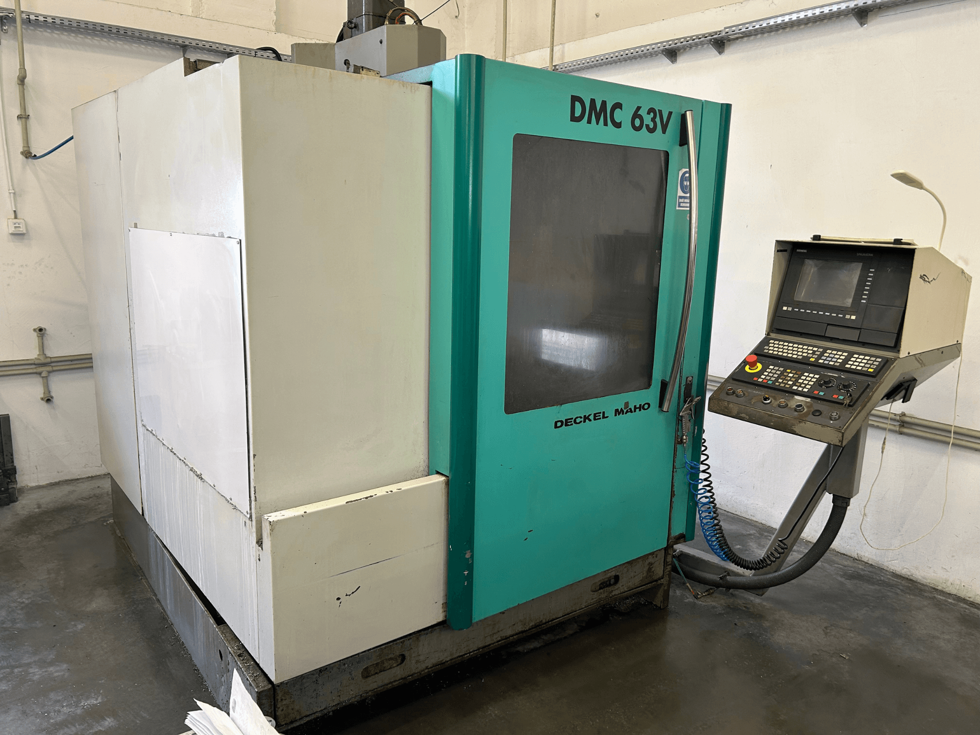 Вертикальний обробний центр DECKEL MAHO DMC 63V у вигляді спереду, з панеллю керування та синьо-зеленим корпусом.