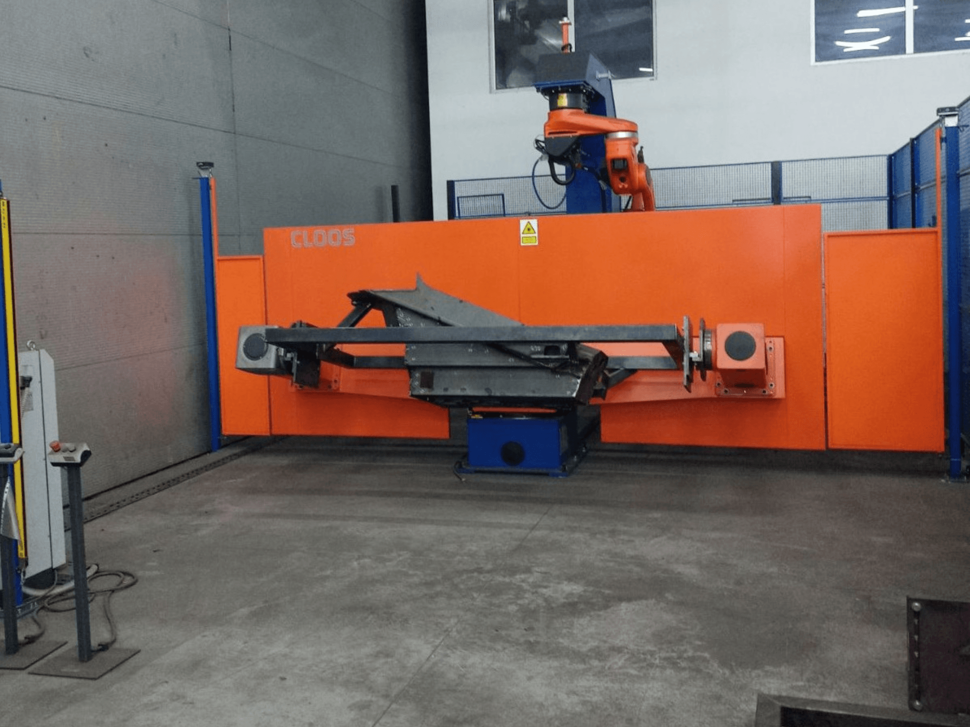 Вид спереду системи автоматизації CLOOS QIROX QRC-350-E з роботизованою рукою та металоконструкцією в промислових умовах.