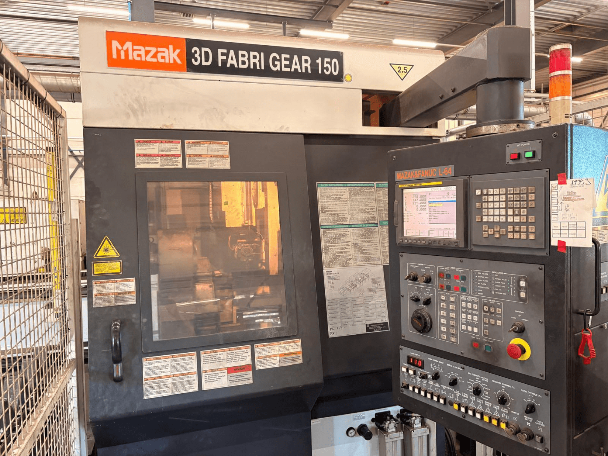 Верстат для різання труб Mazak 3D Fabri Gear 150, вид спереду, на якому видно панель керування, попереджувальні наклейки та робочий інтерфейс.