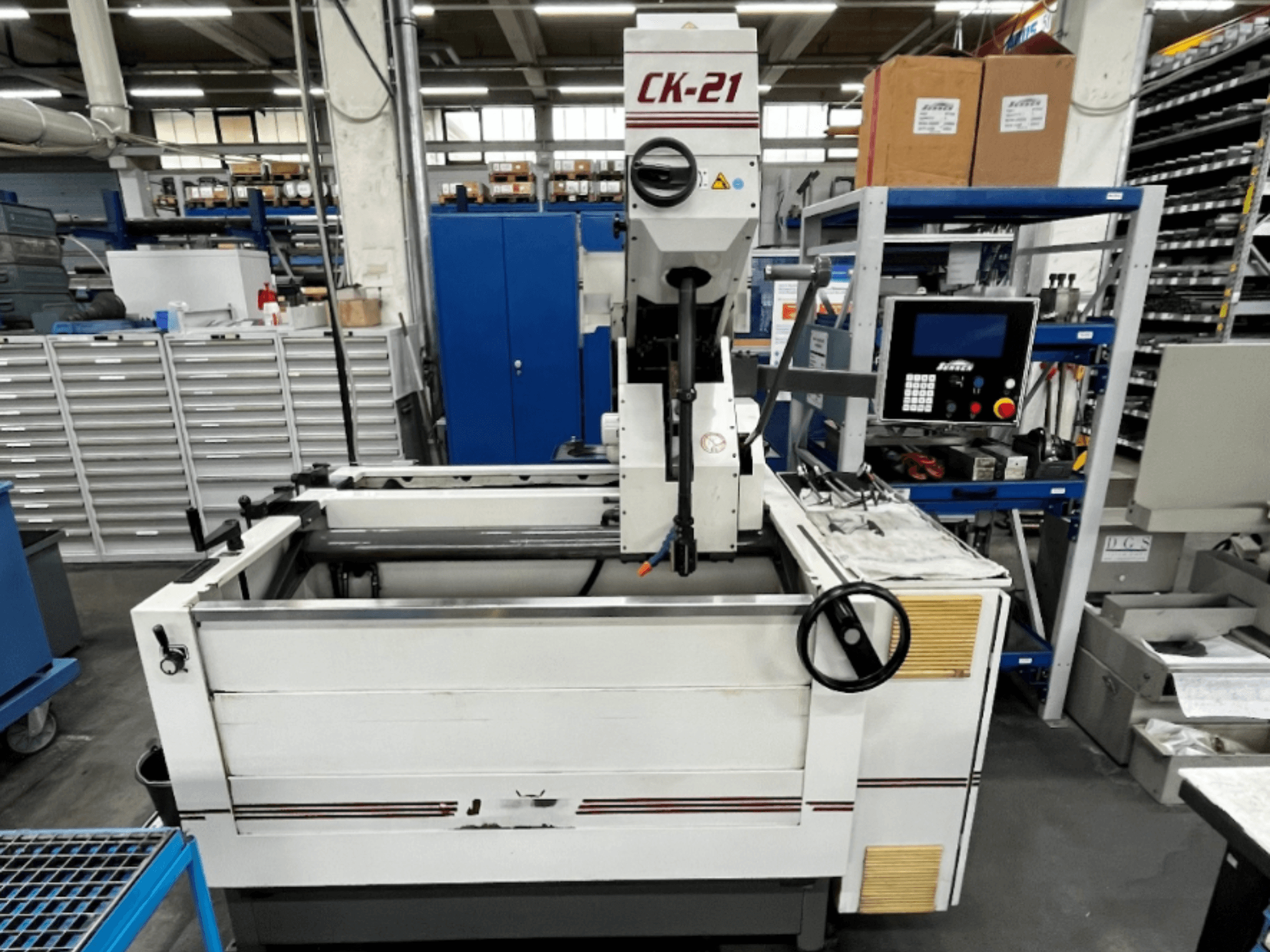 Верстат для вертикального хонінгування Sunnen CK-21-CC спереду, з елементами керування, зоною хонінгування та допоміжним обладнанням на задньому плані.
