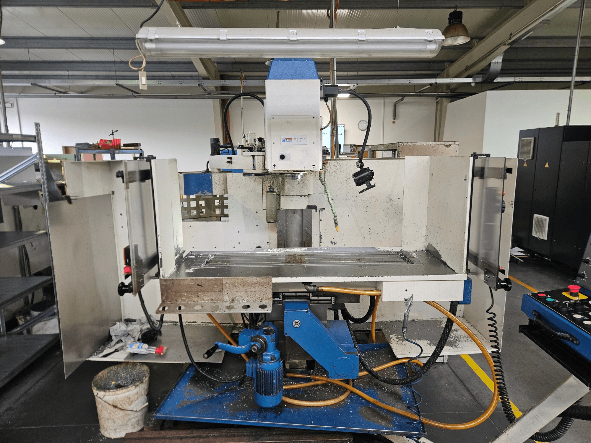 TOS Olomouc FV30 CNC Вертикальний обробний центр у майстерні, вид спереду: панель керування, робочий стіл та система охолодження.