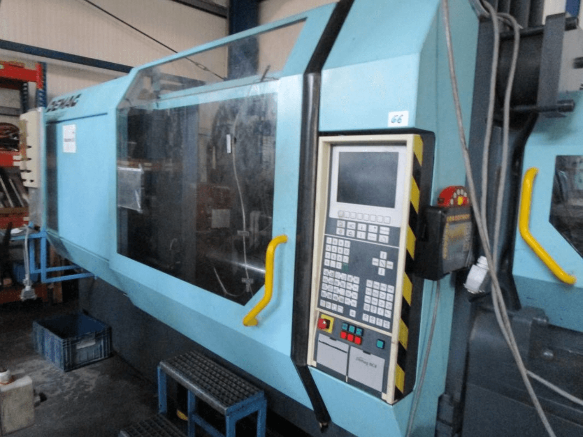 Гідравлічний термопластавтомат Demag Erdotech 500-3300, вид спереду, оснащений панеллю керування та прозорим захисним кожухом.