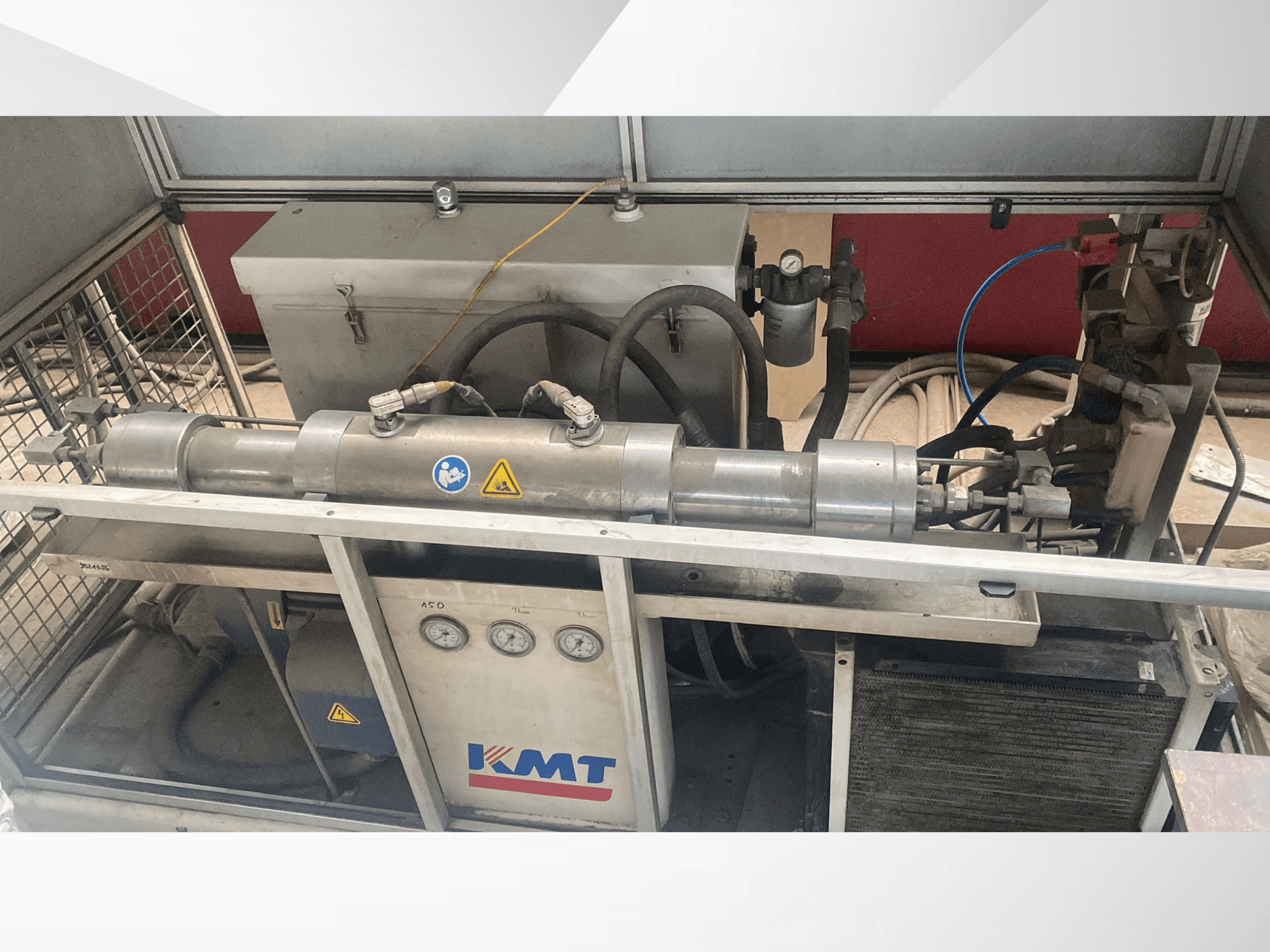 Гідравлічна машина KMT, вид спереду, з манометрами, шлангами та металевим корпусом, ідеально підходить для промислового застосування.