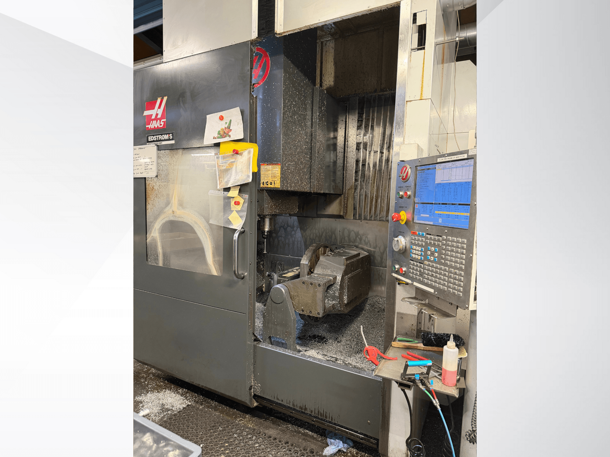 Верстат з ЧПК Haas моделі EDSTROM S, вид спереду, на якому видно металеву заготовку, панель керування та металеву стружку всередині.