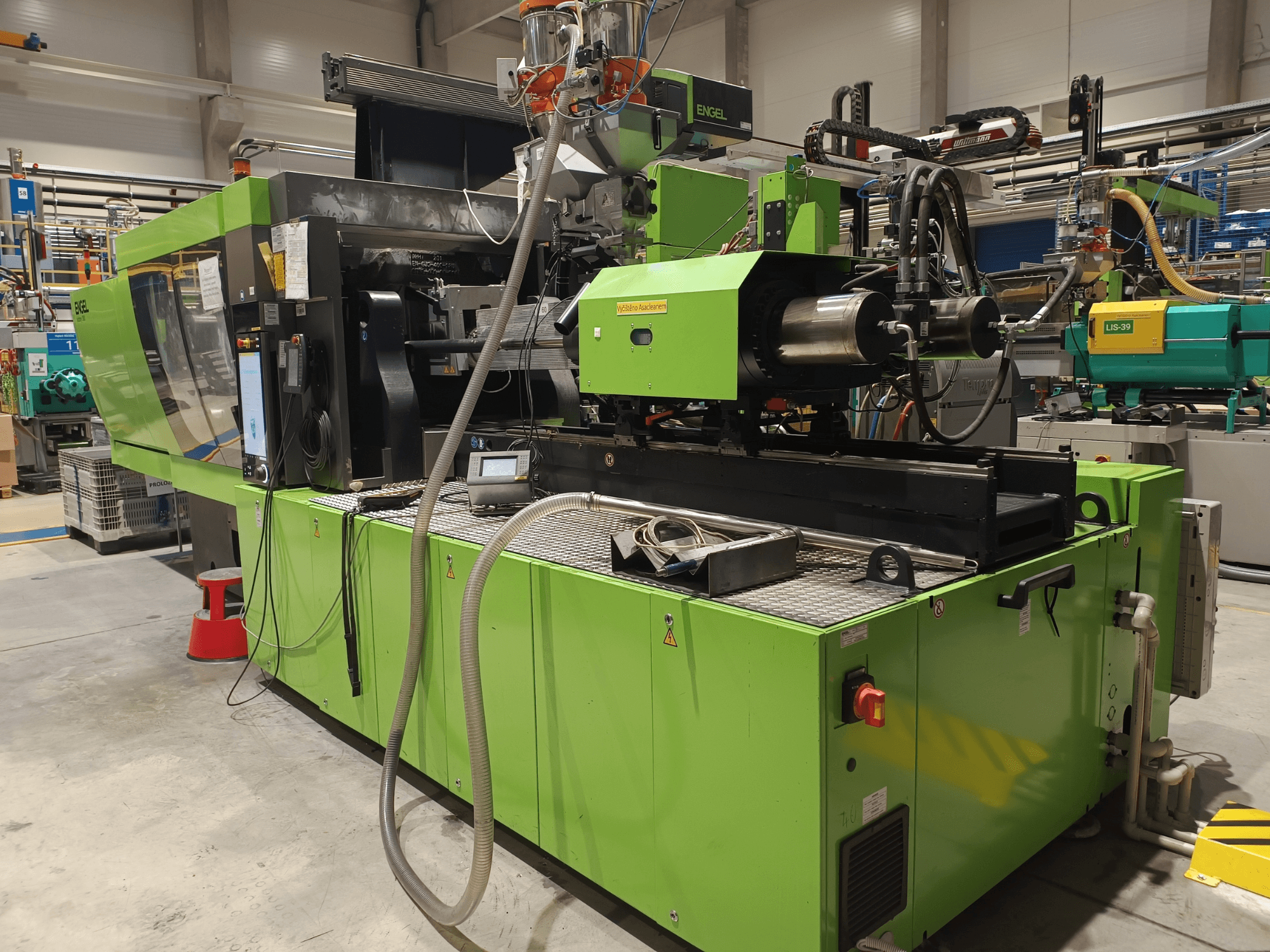 Машина для лиття під тиском Engel, вид збоку, зелений колір, видно сенсорну панель і гідравлічні компоненти.