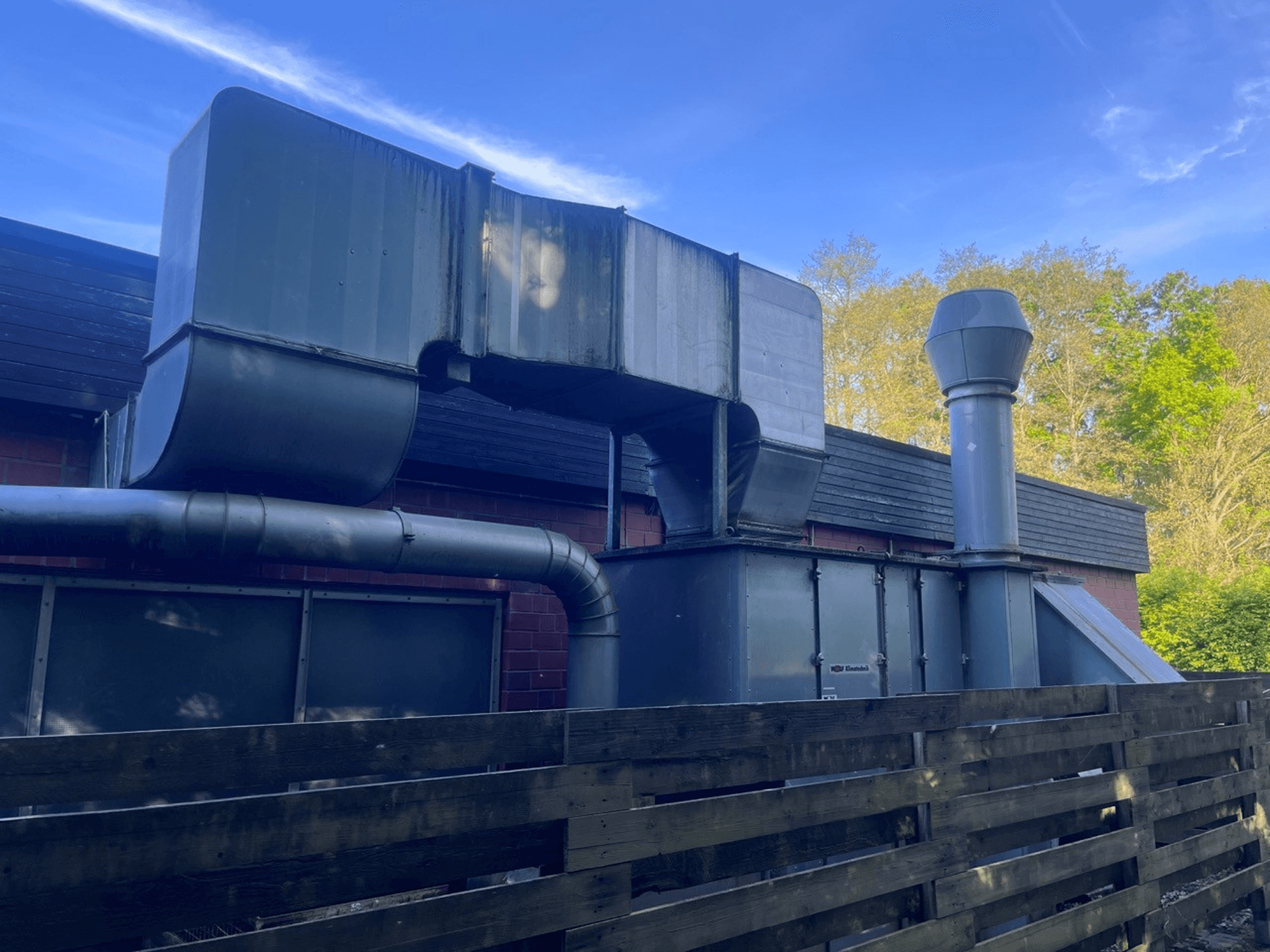 Промислова вентиляційна система з металевими повітроводами, вид збоку; включає квадратний і циліндричний димохід, зелене покриття.