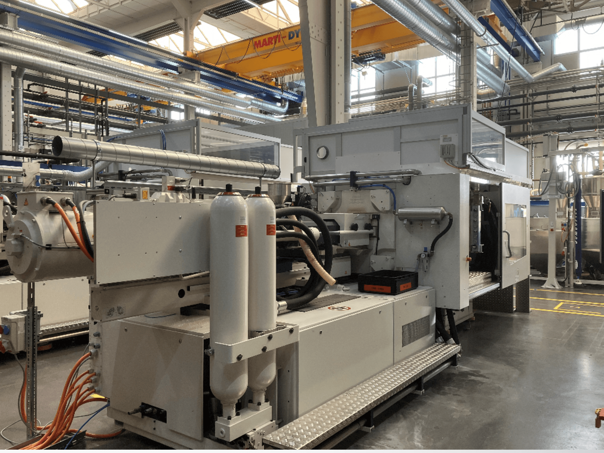 Промислова машина показана у вигляді збоку з кількома шлангами, двома вертикальними баками та панеллю керування; марку/модель не видно.