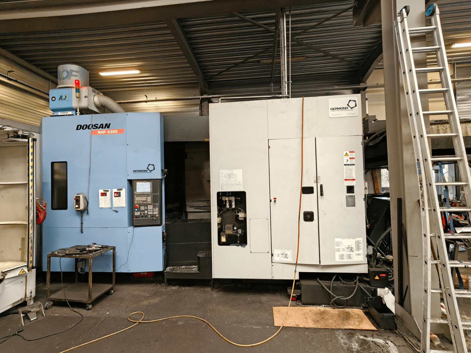 Горизонтальний обробний центр DOOSAN NHP6300 у фронтальному ракурсі, на якому видно панель управління та сусіднє обладнання в умовах цеху.