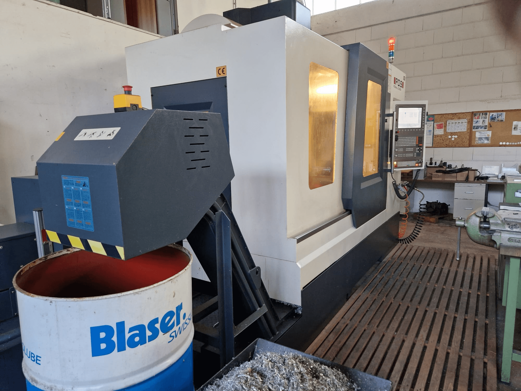 Вид спереду вертикального обробного центру POSmill C 1050 з системою охолодження над барабаном Blaser і панеллю керування.