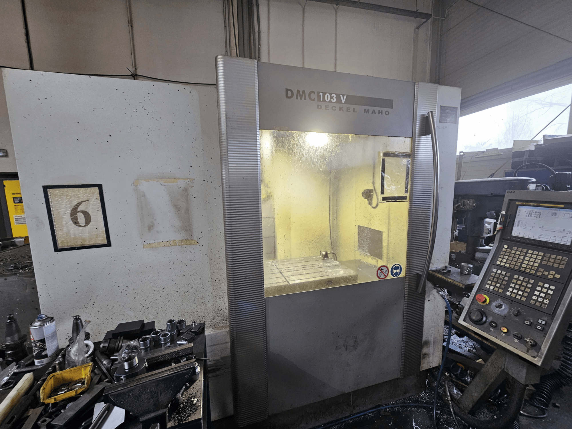 Вид спереду верстата з ЧПК Deckel Maho DMC 103 V, з панеллю керування, робочою зоною та цифровим індикатором "6".