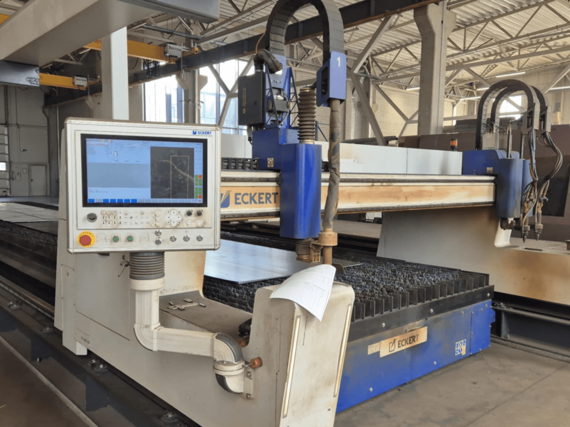Панель керування розкрійним верстатом ECKERT з ЧПУ, вид спереду, з сенсорним дисплеєм і різними операційними кнопками.