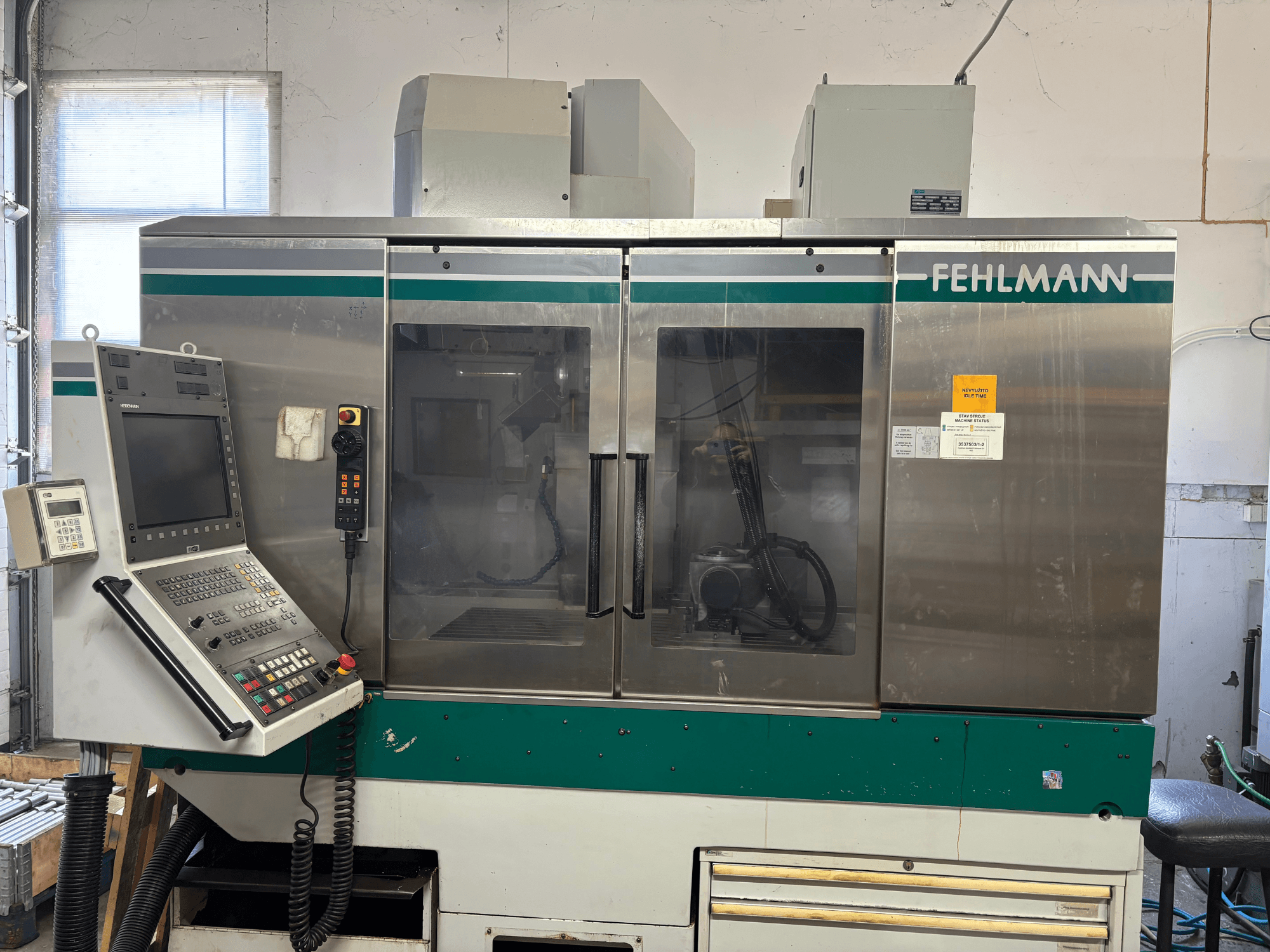 Вигляд спереду вертикального обробного центру FEHLMANN Picomax 90-M із панеллю керування, прозорим кожухом та кнопками управління.
