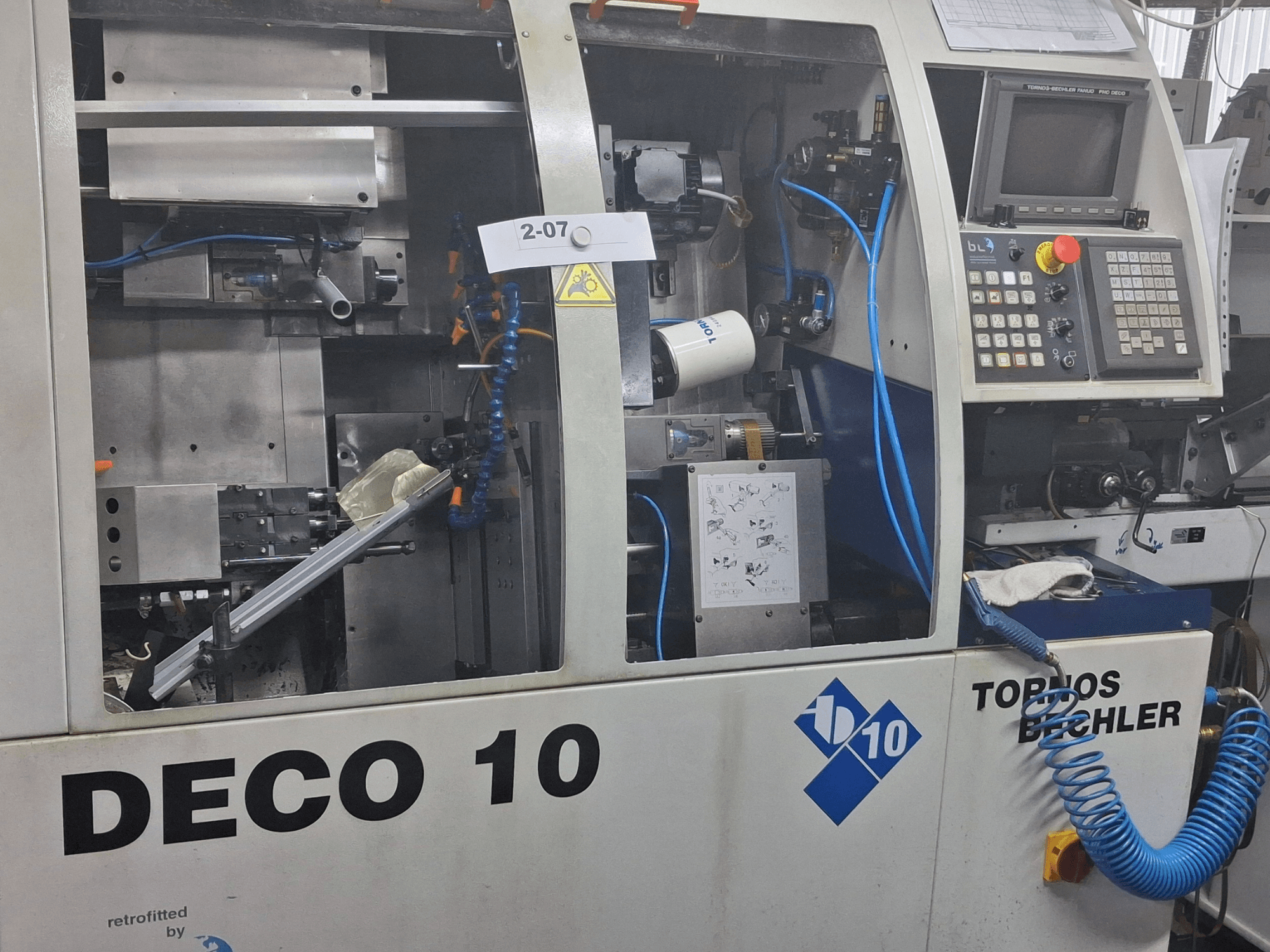 Токарний верстат швейцарського типу TORNOS Deco 10a крупним планом, демонструє внутрішній механізм і деталі панелі керування.