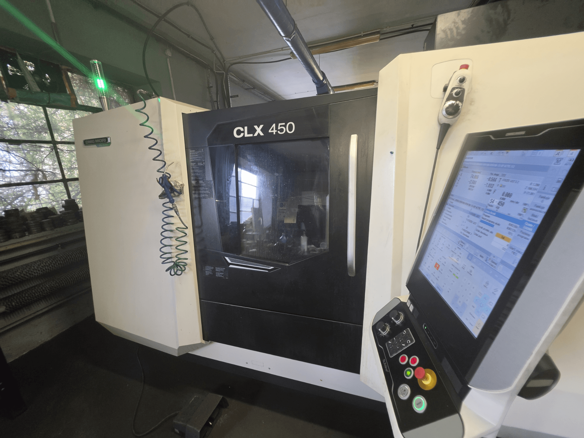 Горизонтальний токарний верстат DMG MORI CLX 450 V3, вид спереду з панеллю керування та монітором, на якому відображаються робочі дані.