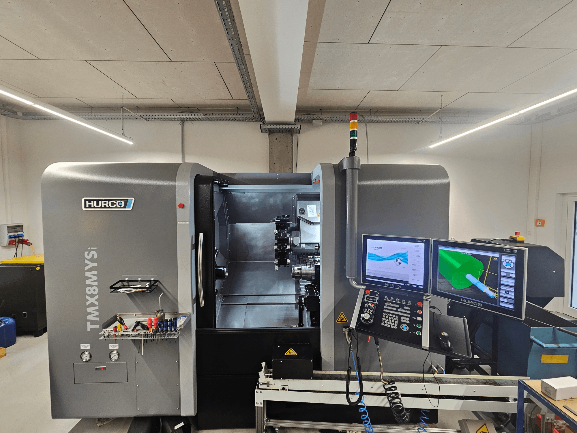 Токарно-фрезерний центр Hurco TMX 8 MYSi в майстерні з двома моніторами, панеллю керування та інструментами збоку.