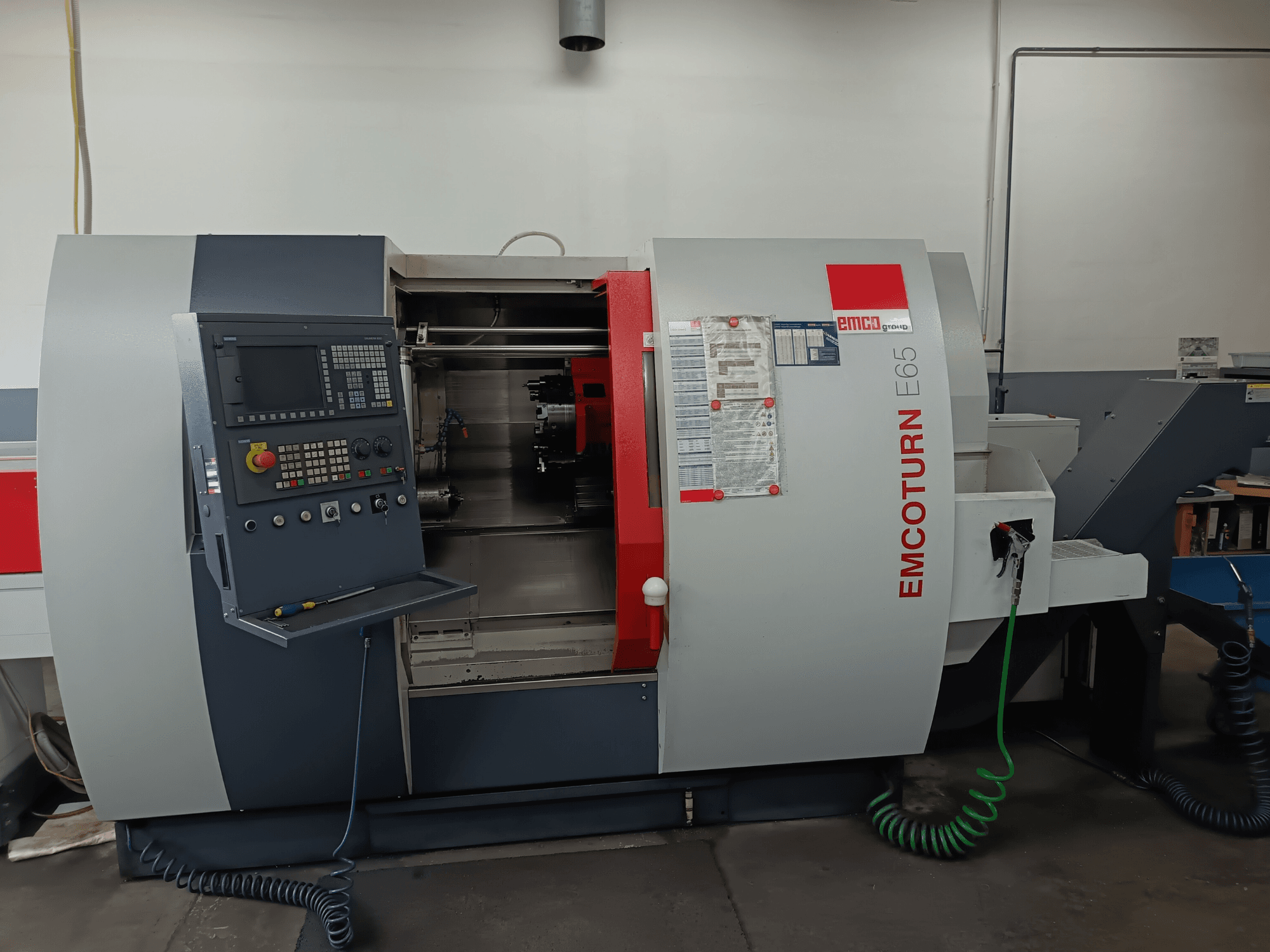 Токарно-фрезерний центр EMCO EMCOTURN E65, вид спереду з панеллю керування, внутрішнім механізмом і функціями в умовах майстерні.