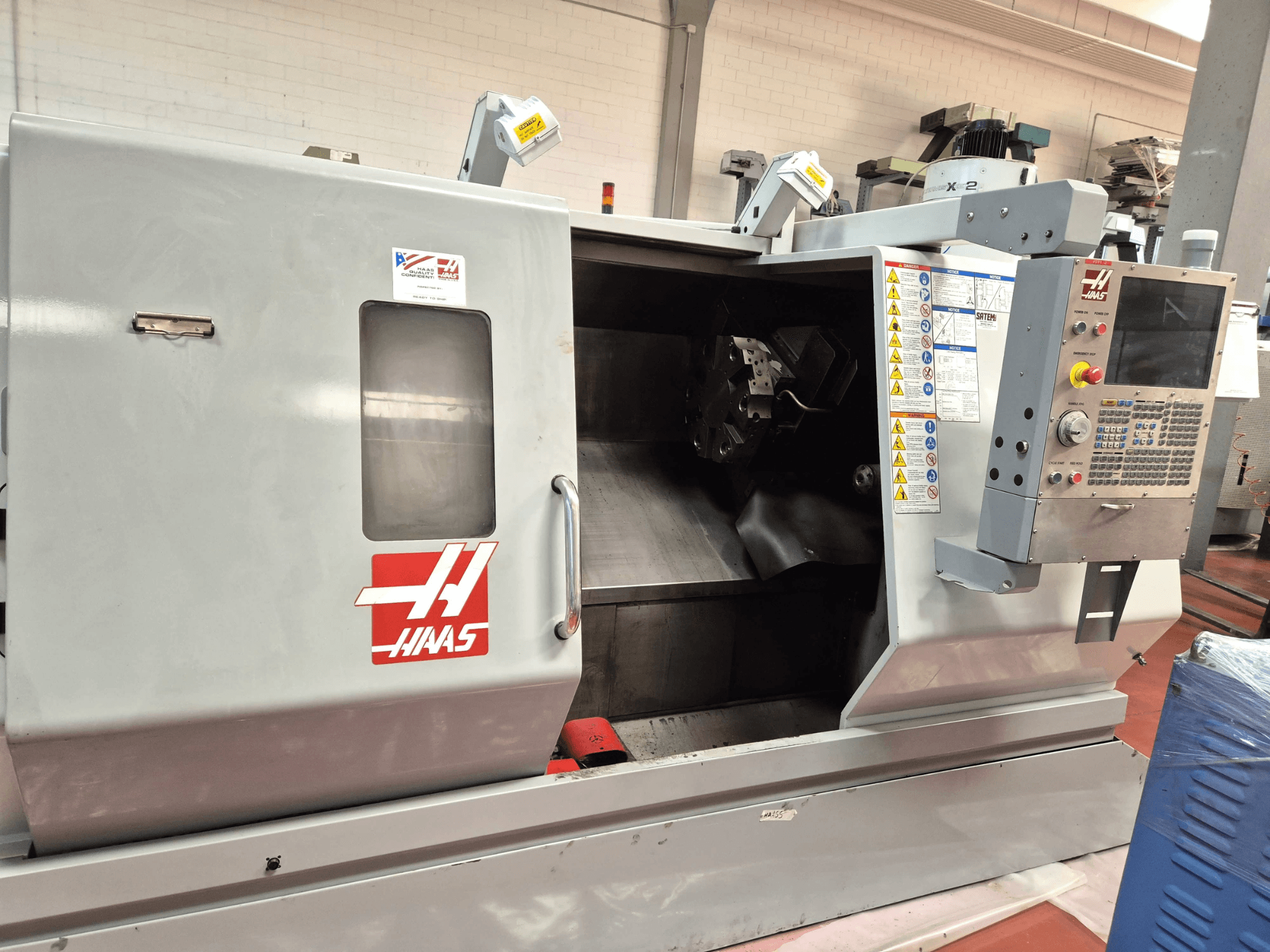 Горизонтальний токарний верстат Haas SL 30TBHE, вид спереду, на якому видно органи управління та відкритий відсік для виконання токарних операцій.
