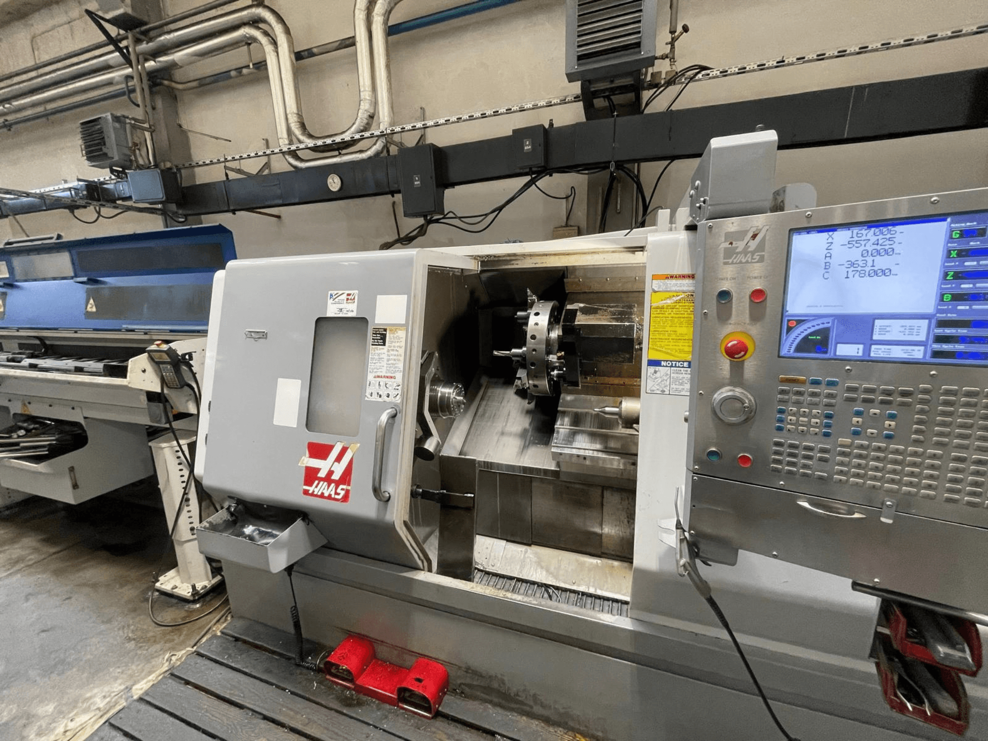 Горизонтальний токарний верстат Haas SL-30THE у цеху, оснащений цифровою панеллю керування та відкритою робочою зоною.