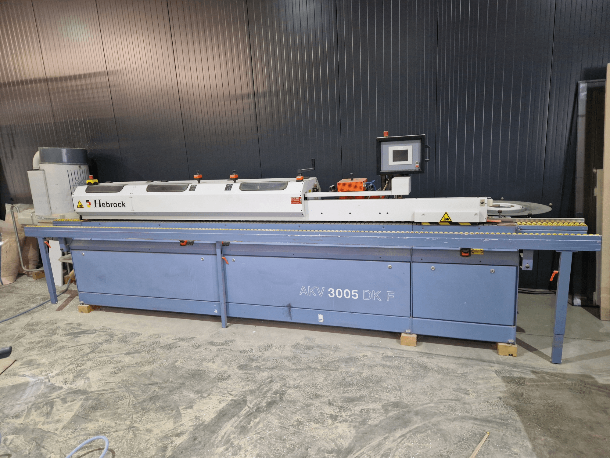 Кромкооблицювальний верстат HEBROCK AKV 3005 DK-F, вигляд спереду, з панеллю керування, стрічкою подачі та регульованими налаштуваннями.