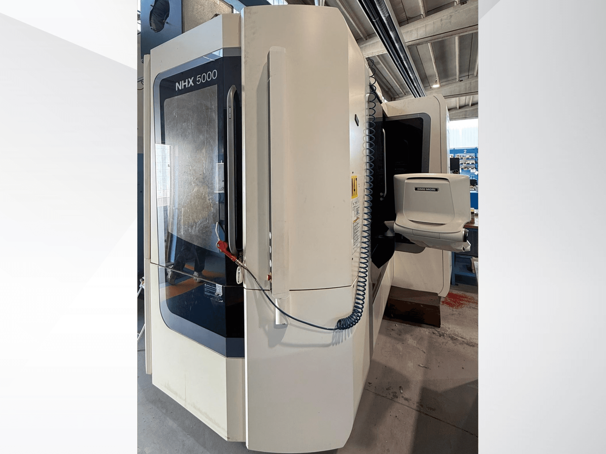 Горизонтальний токарний верстат DMG MORI NHX 5000, вид спереду, на якому видно панель управління та тримач шпинделя.