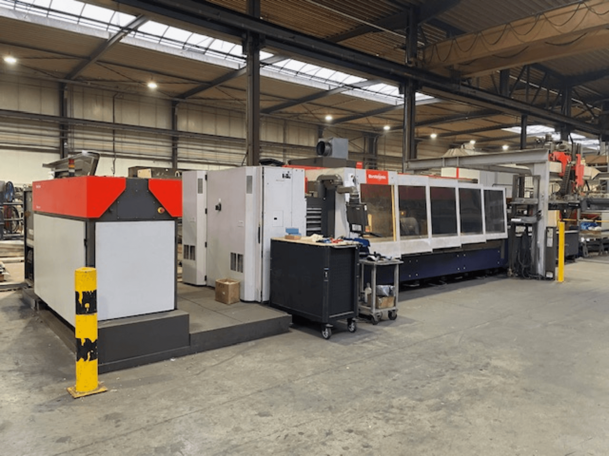 Машина для лазерного різання CO2 Bystronic BySpeed 3015, вид збоку в майстерні, з виразними червоними та сірими елементами дизайну.