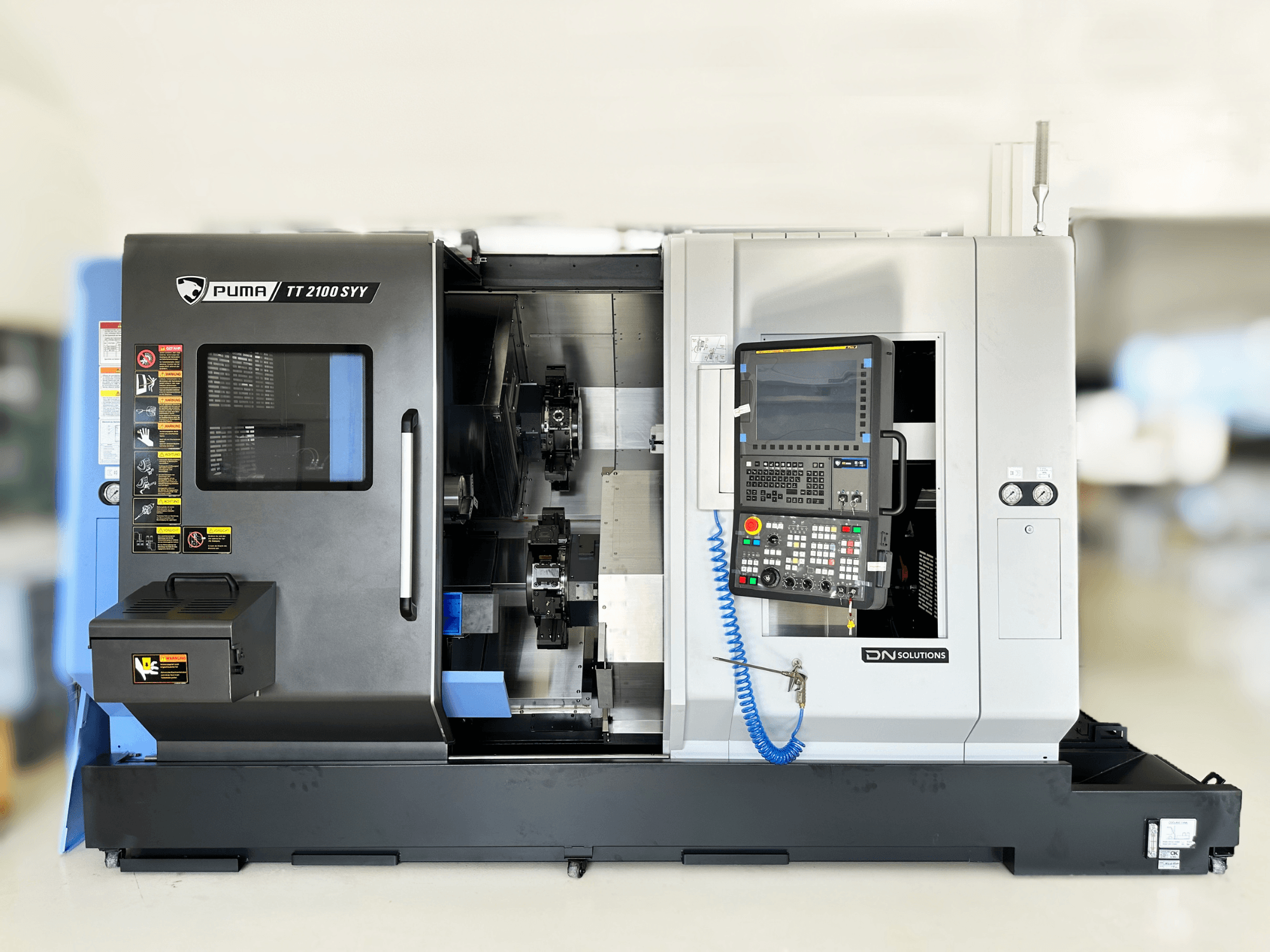 Токарно-фрезерний центр DN SOLUTIONS PUMA TT2100SYY вид спереду, з панеллю керування та видимими внутрішніми компонентами.