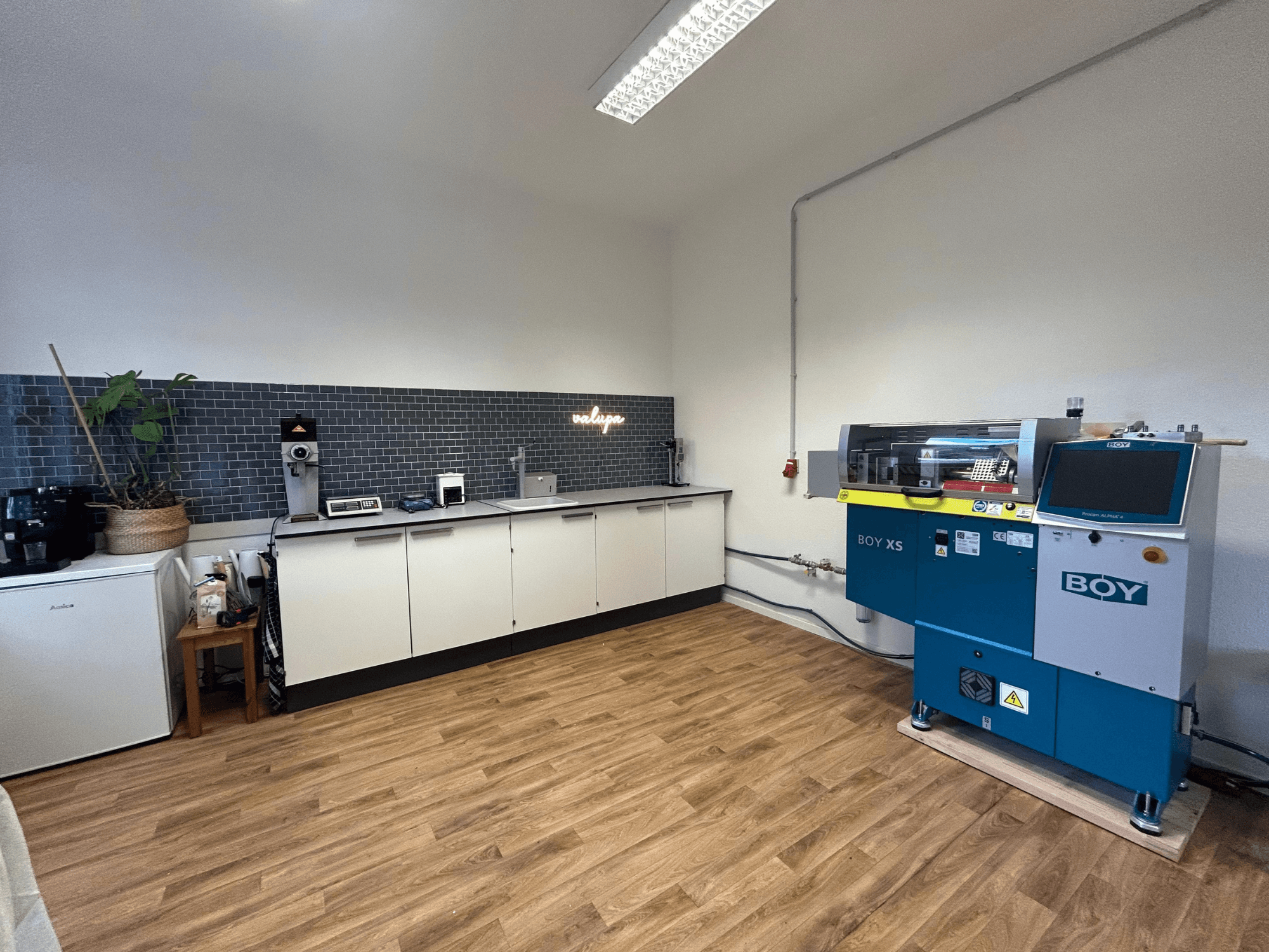 Гідравлічний термопластавтомат BOY XS 161, вид спереду, на сучасній кухні з побутовою технікою та дерев'яною підлогою.