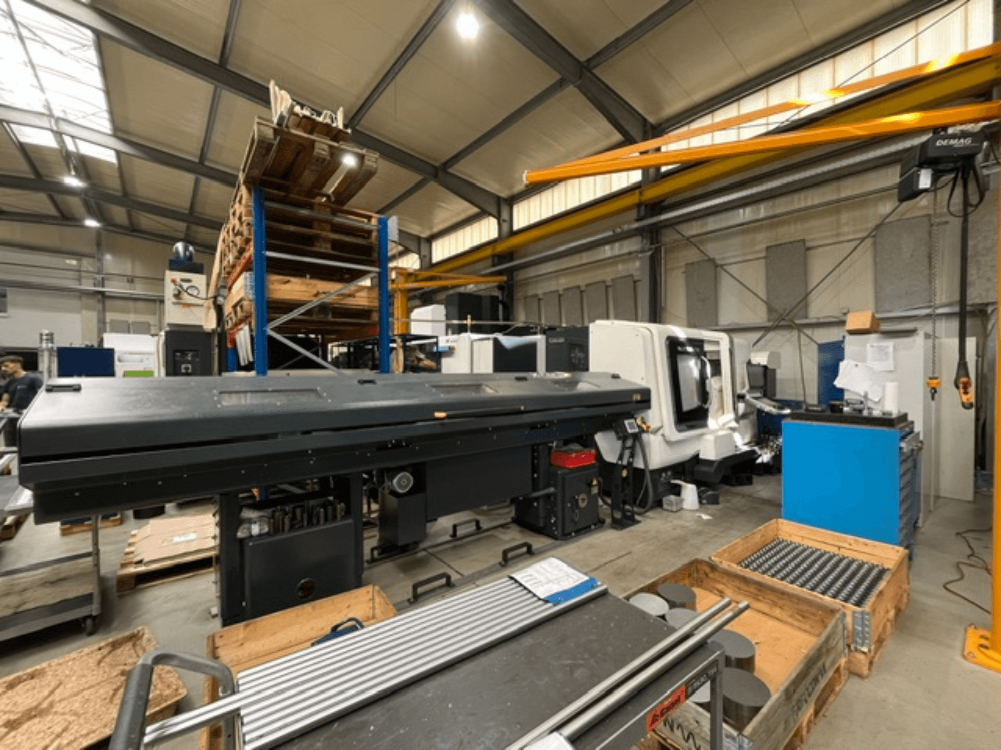 Горизонтальний токарний верстат DMG MORI MORI NLX 2500/700 SY у заводській комплектації, вид збоку, на якому видно інструменти та палети.