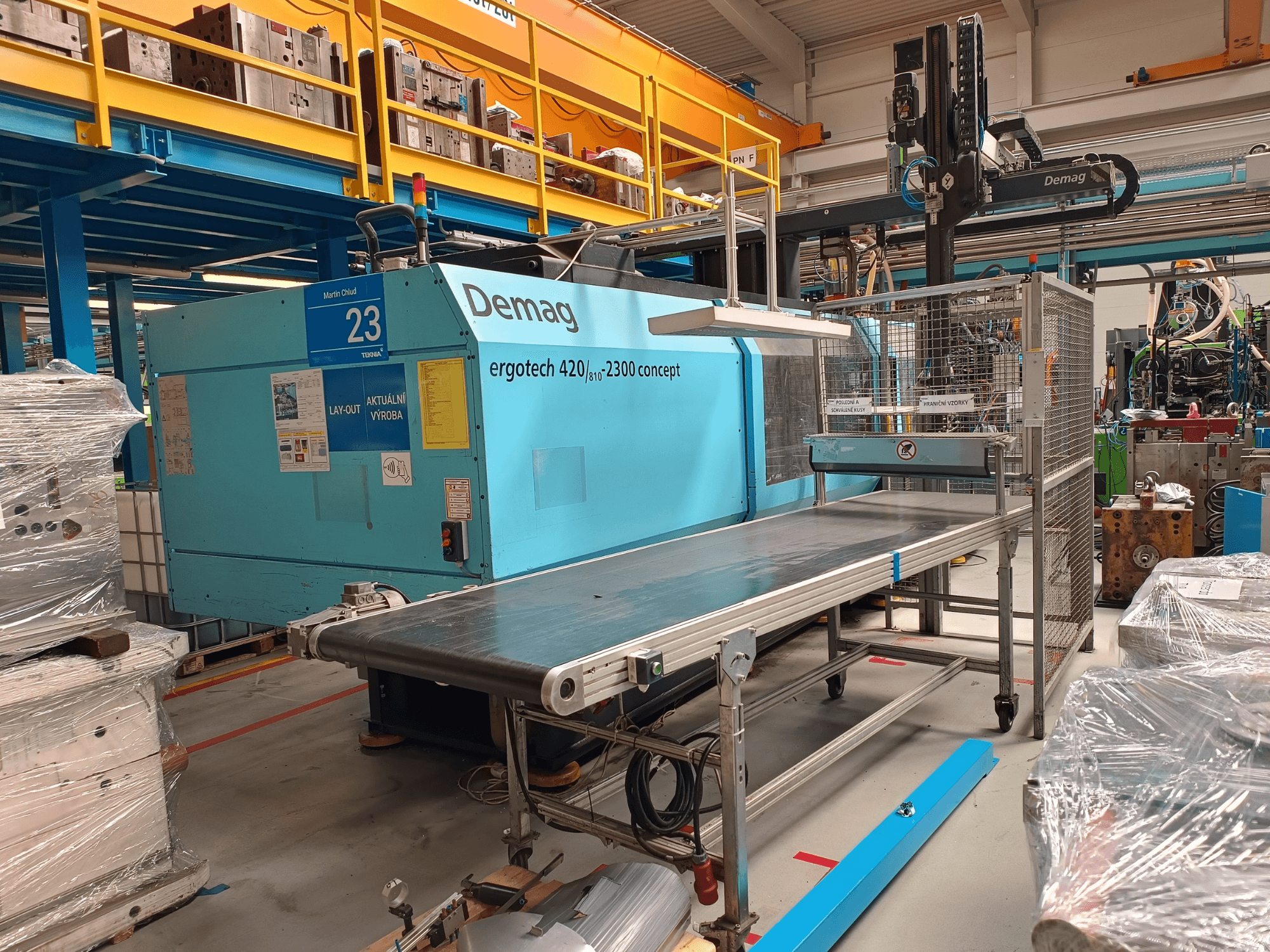 Гідравлічний термопластавтомат Demag ergotech 420/810 - 2300 у вигляді збоку, з конвеєром і захисним кожухом.