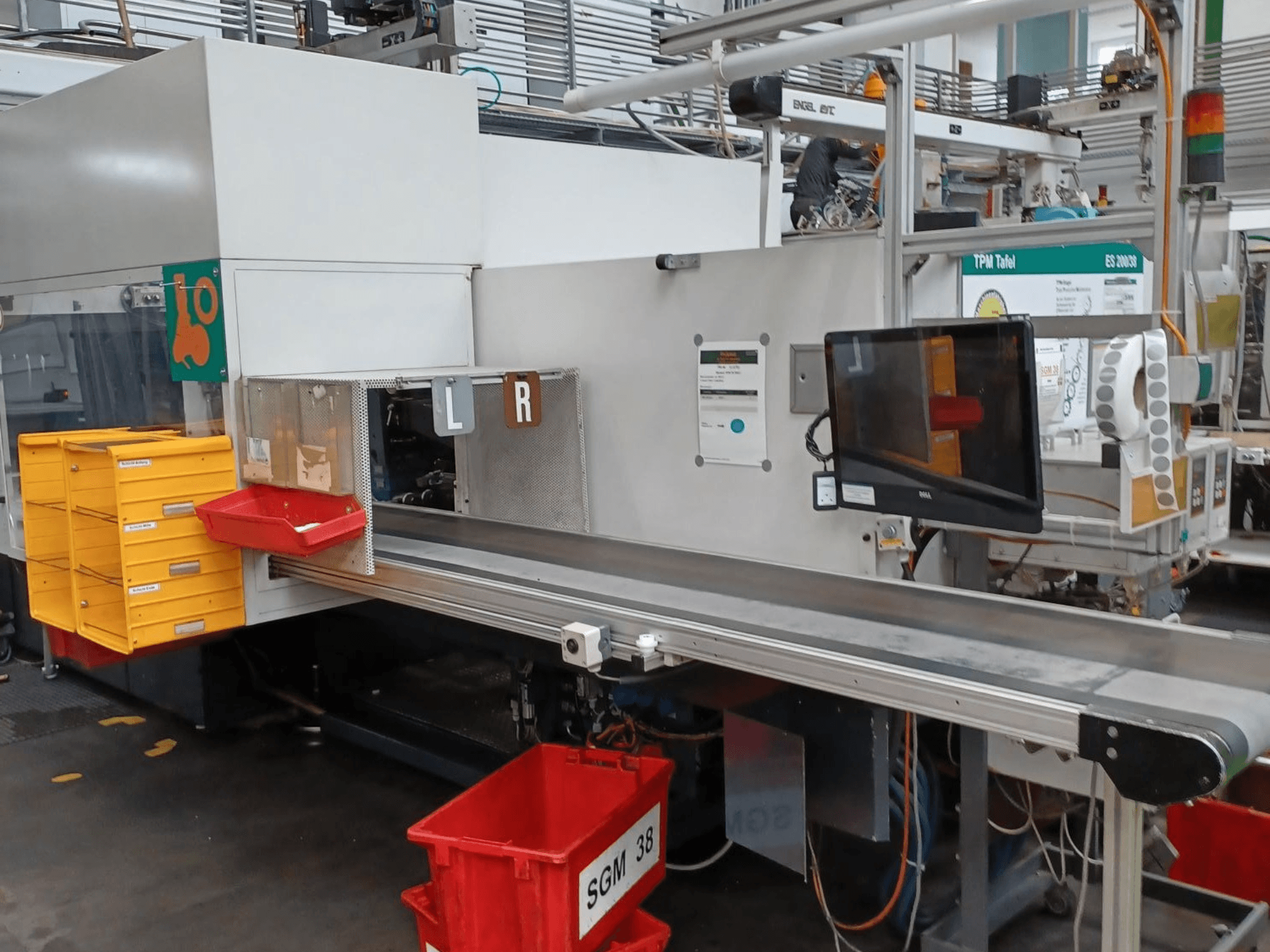Промислова сортувальна машина з жовтим і червоним контейнерами, вид збоку, з монітором управління і маркованими відсіками для сортування.