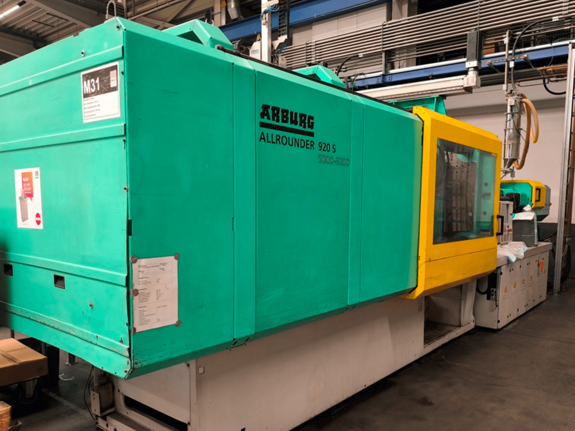 Термопластавтомат Arburg Allrounder 920 S блакитно-жовтого кольору, вид збоку з панеллю керування та компонентами.