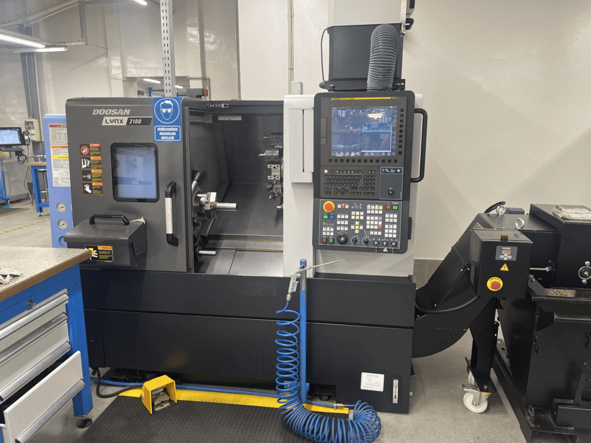 Вид спереду горизонтального токарного верстата DOOSAN Lynx 2100A, що демонструє панель керування та зону шпинделя з помітними функціями безпеки.
