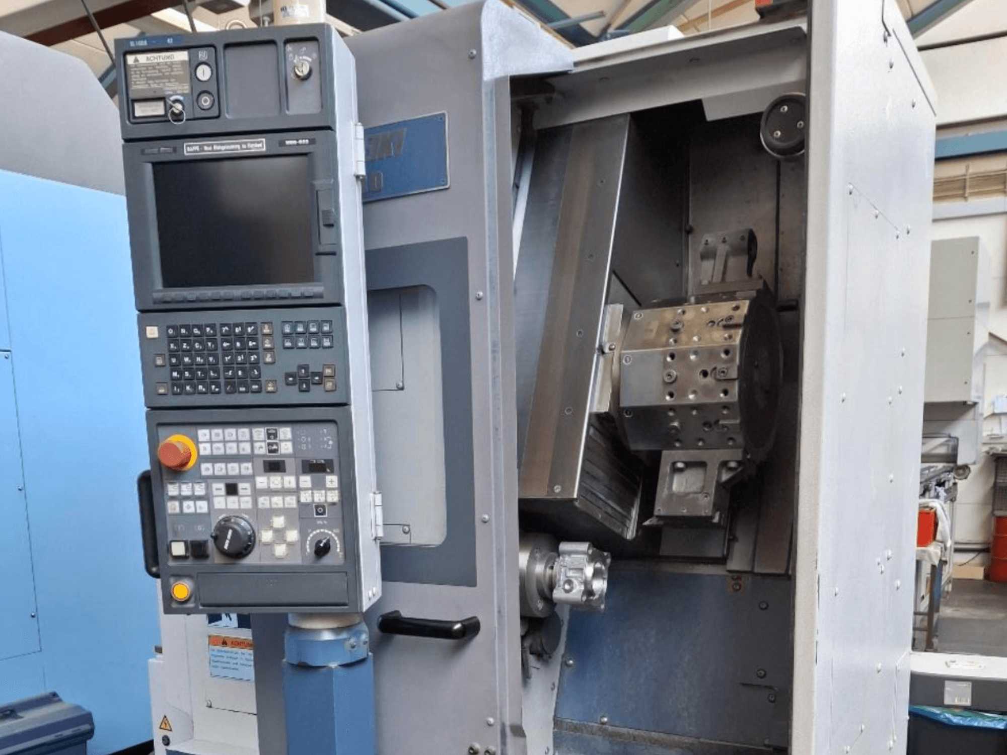 Горизонтальний токарний верстат MORI SEIKI SL 1000 вид спереду, з панеллю керування та детальним внутрішнім механізмом.
