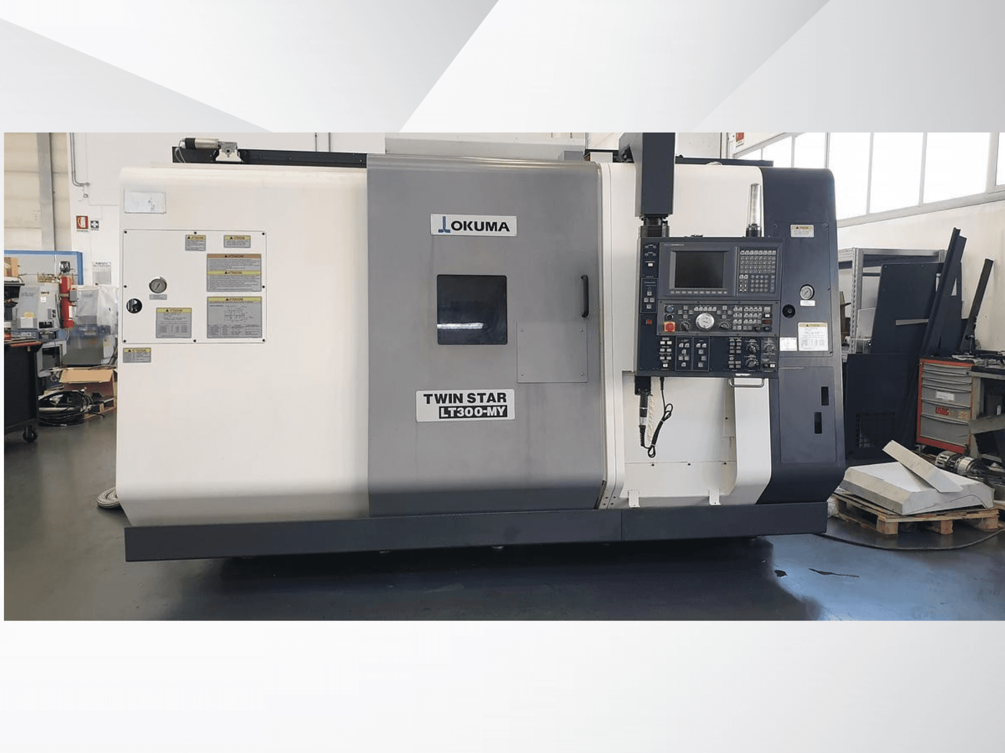 Токарний верстат з ЧПУ Okuma Twin Star LT300-MY, вид спереду з панеллю керування та робочими етикетками.