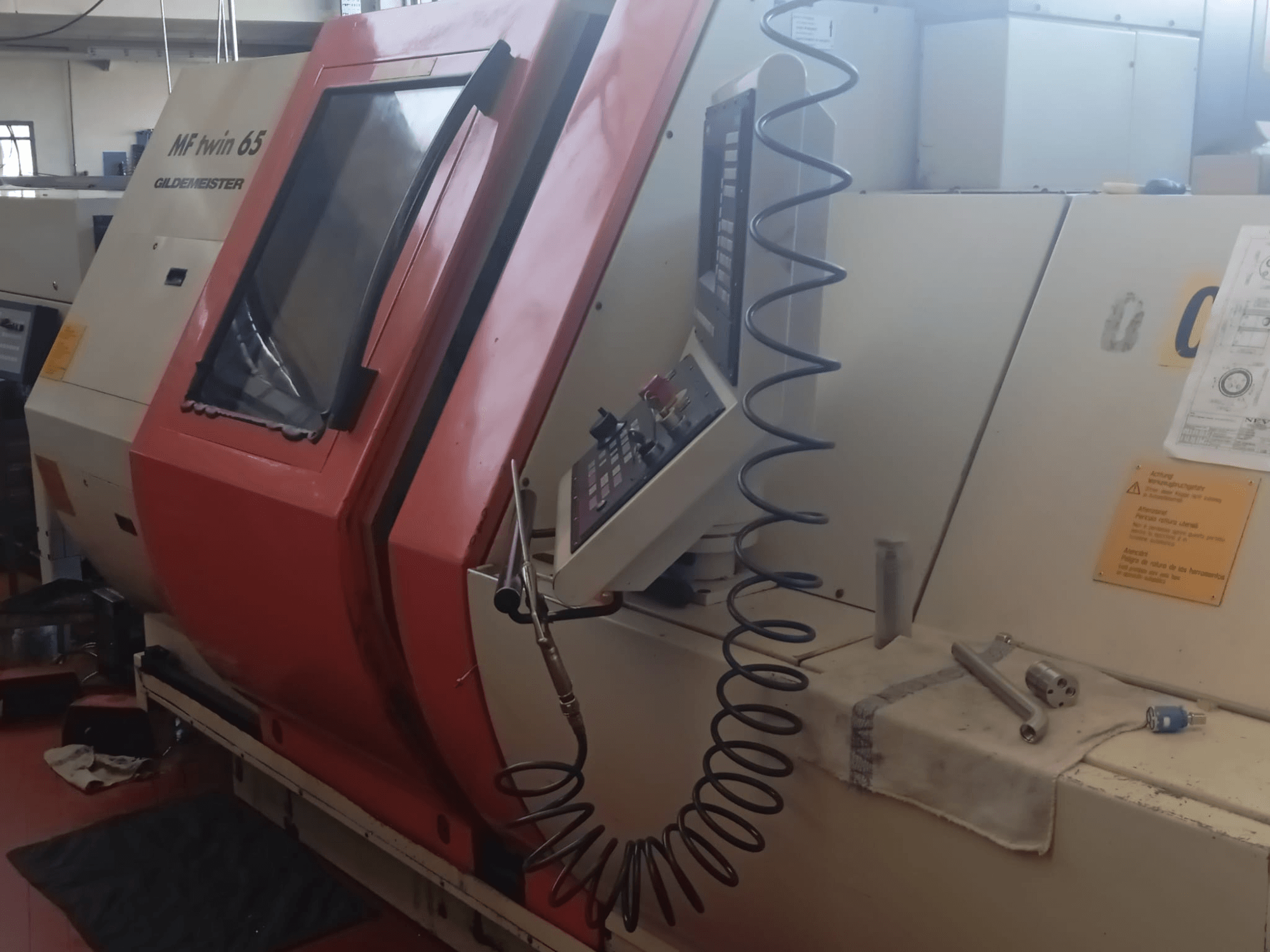 Помаранчево-біла машина MF twin 65 Gliedemeister, вид спереду, з панеллю керування та інструментами на тканині.