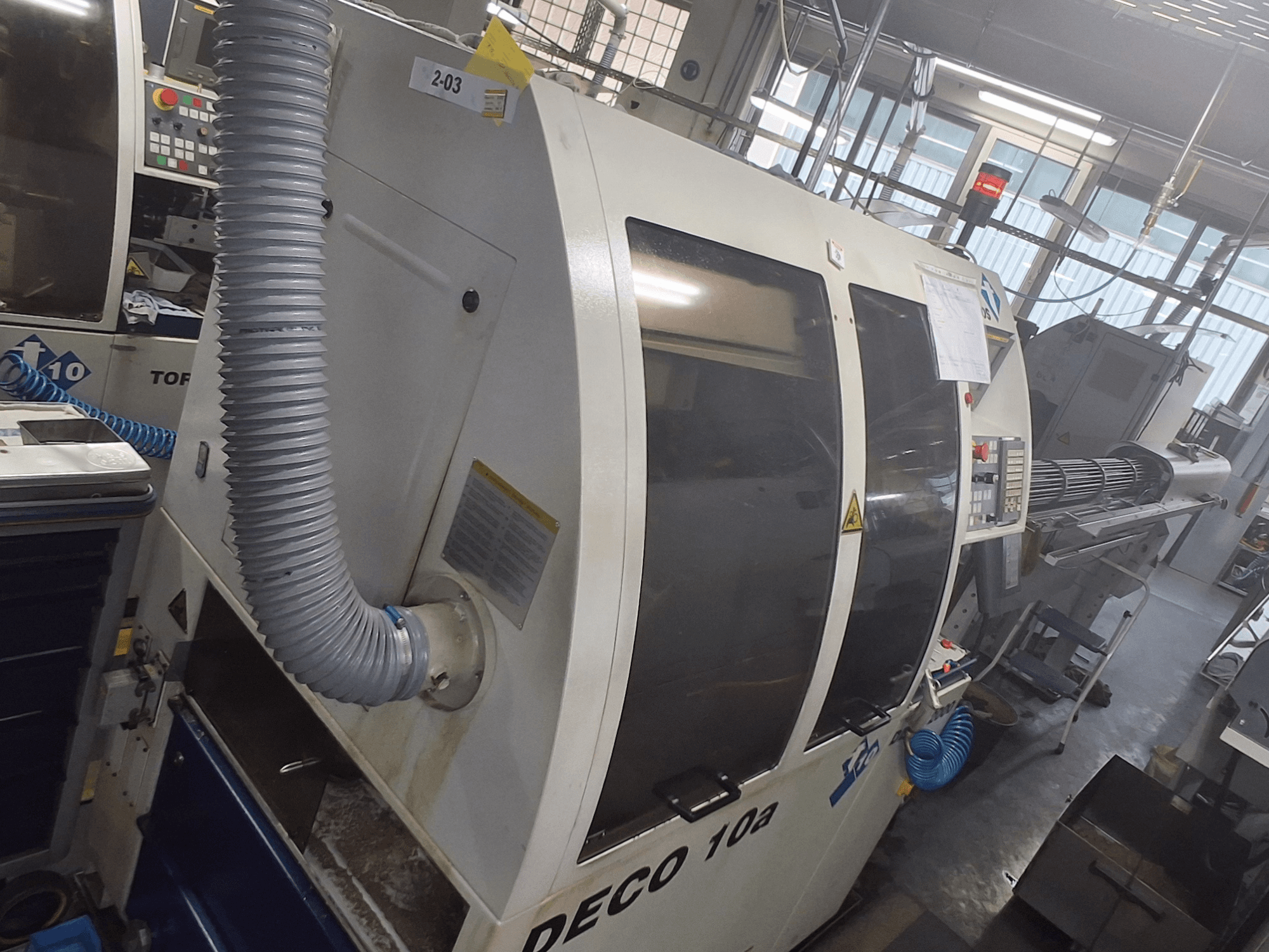 Машина DECO 10a у вигляді спереду; велика панель керування, повітропроводи та експлуатаційні наклейки.