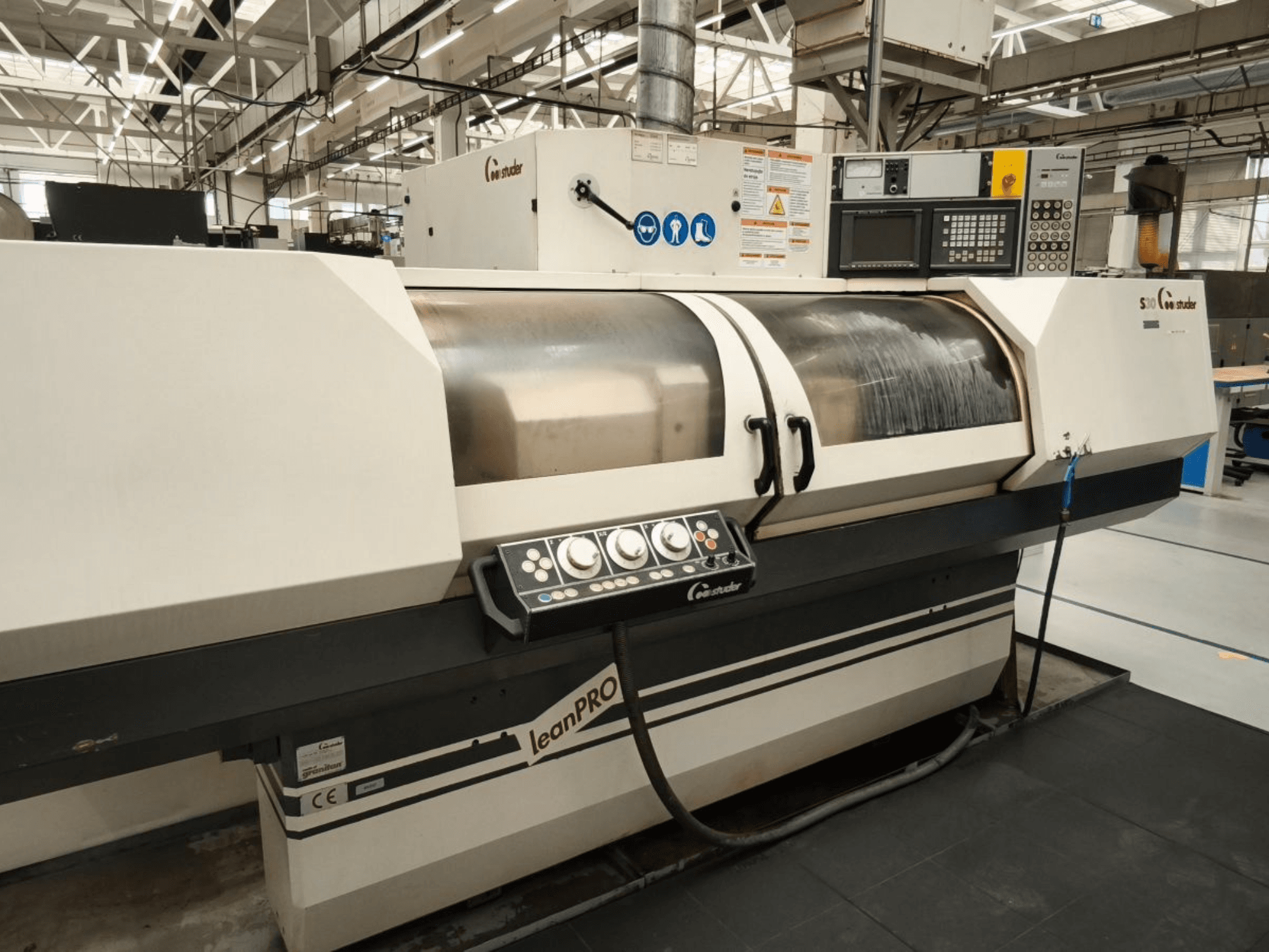 Циліндрична шліфувальна машина STUDER S30 LEAN PRO, вид збоку, демонструє панель керування та кришку шліфувального круга в промислових умовах.