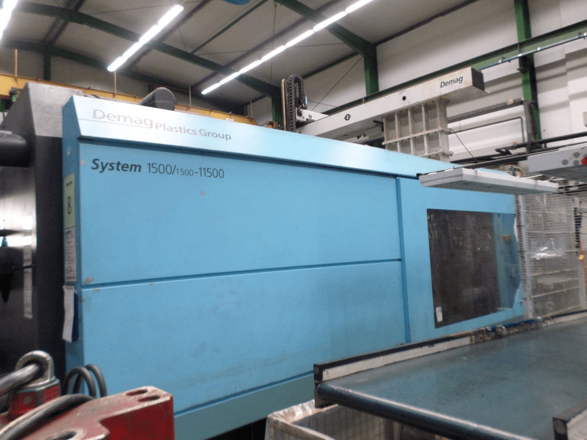 Гідравлічна термопластавтомат Demag D 650 синього кольору, бічний вигляд із позначкою «System 1500/1500-11500» та робочою зоною.
